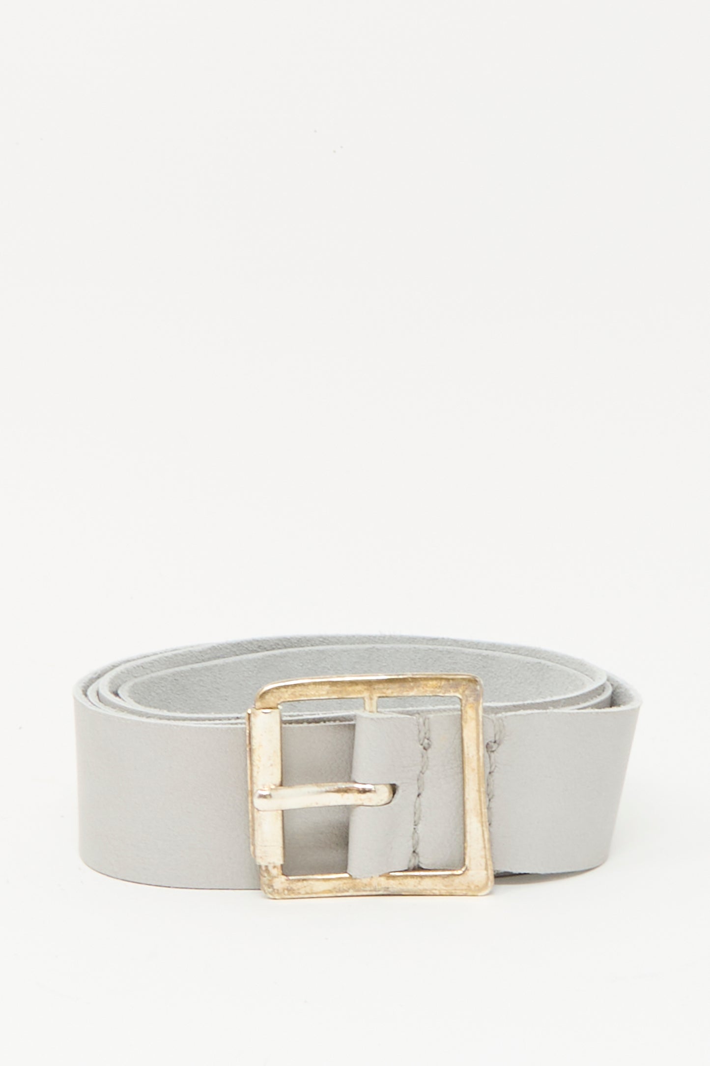 The Lauren Manoogian Plata Belt in Gris, featuring a handmade silver buckle and crafted from light gray leather in Peru, is shown rolled up against a plain white background.
