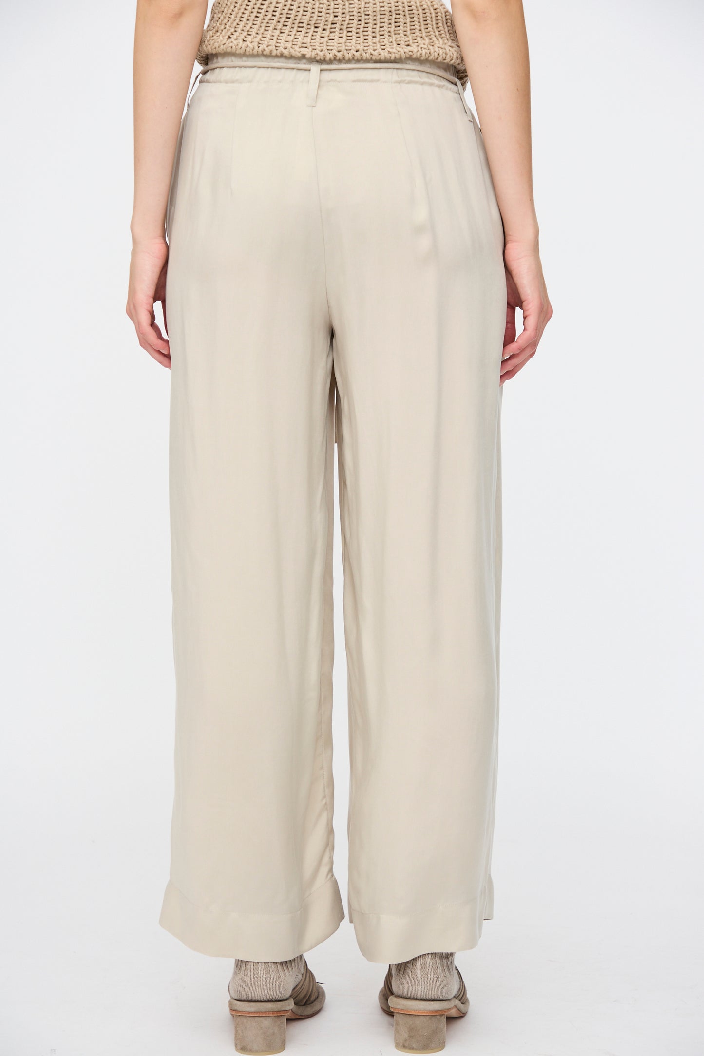 Model wearing Lauren Manoogian Sanded Trouser in Sisal and sandals, shown from the back against a plain white background.