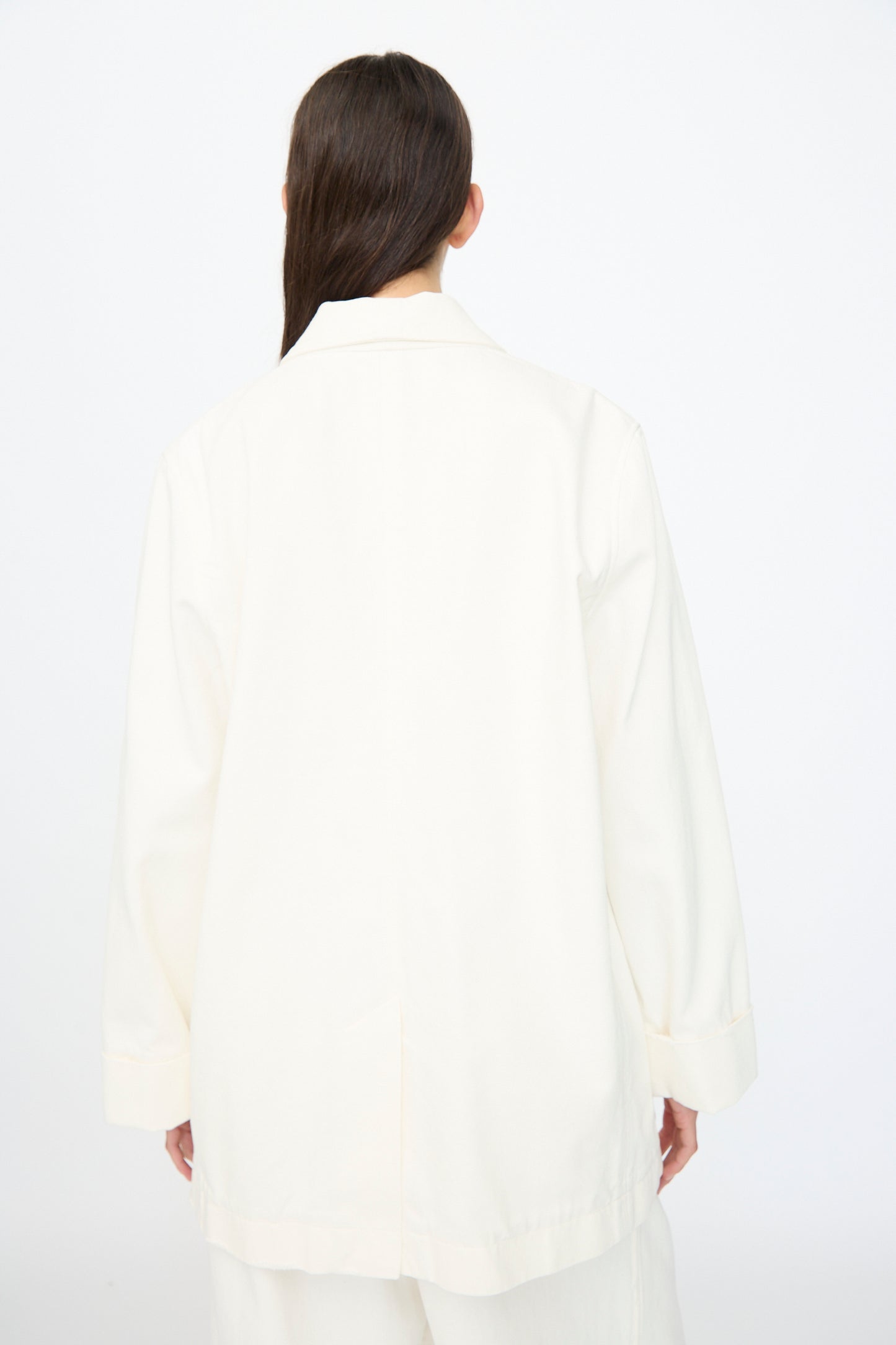 A person with long brown hair wearing the Lauren Manoogian Washed Jacket in White is photographed from behind against a plain white background.