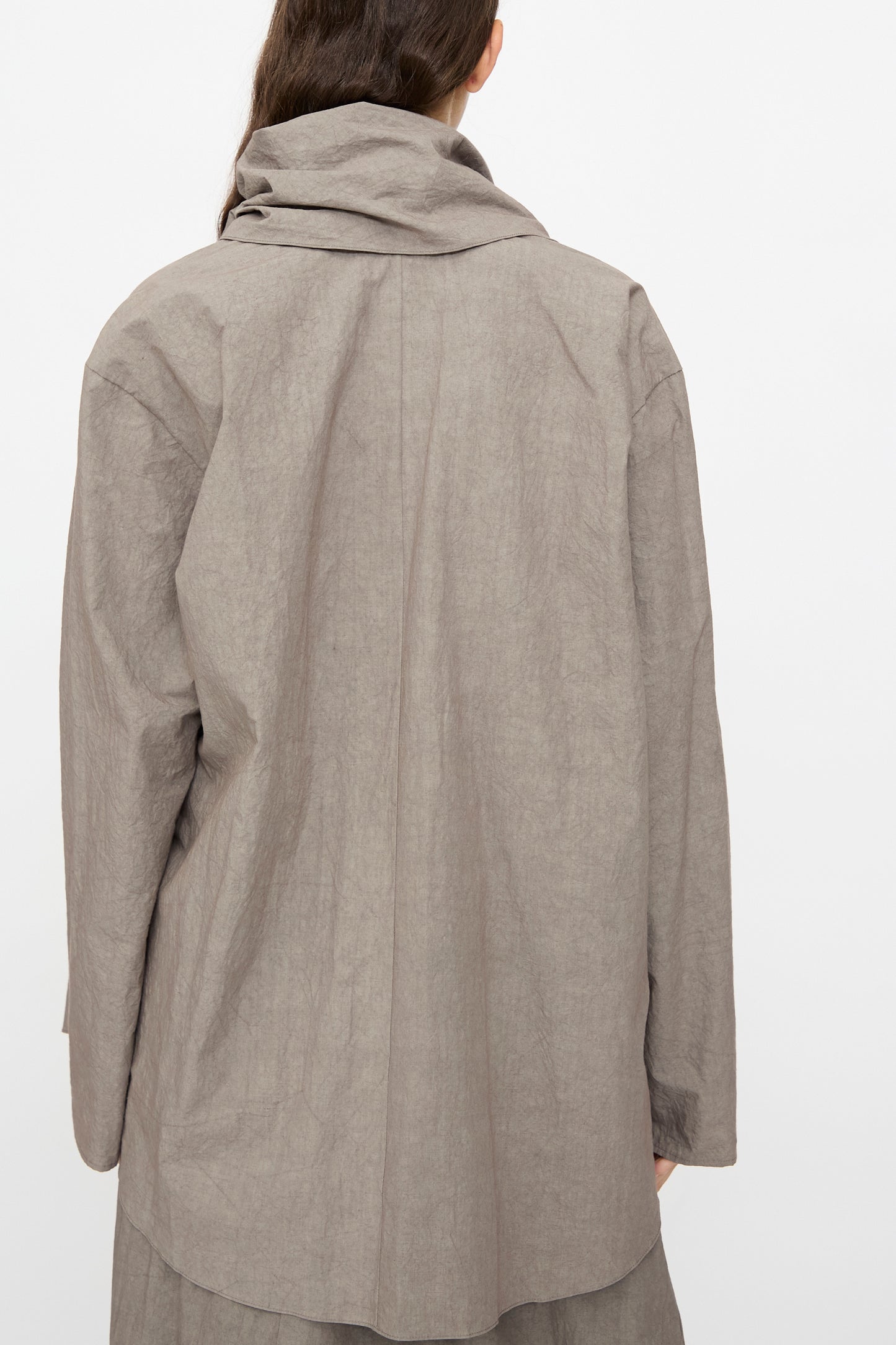 A person is photographed from the back against a plain white background, wearing the Lauren Manoogian Wrap Top in Cinder—a loose-fitting, long sleeve cotton top.