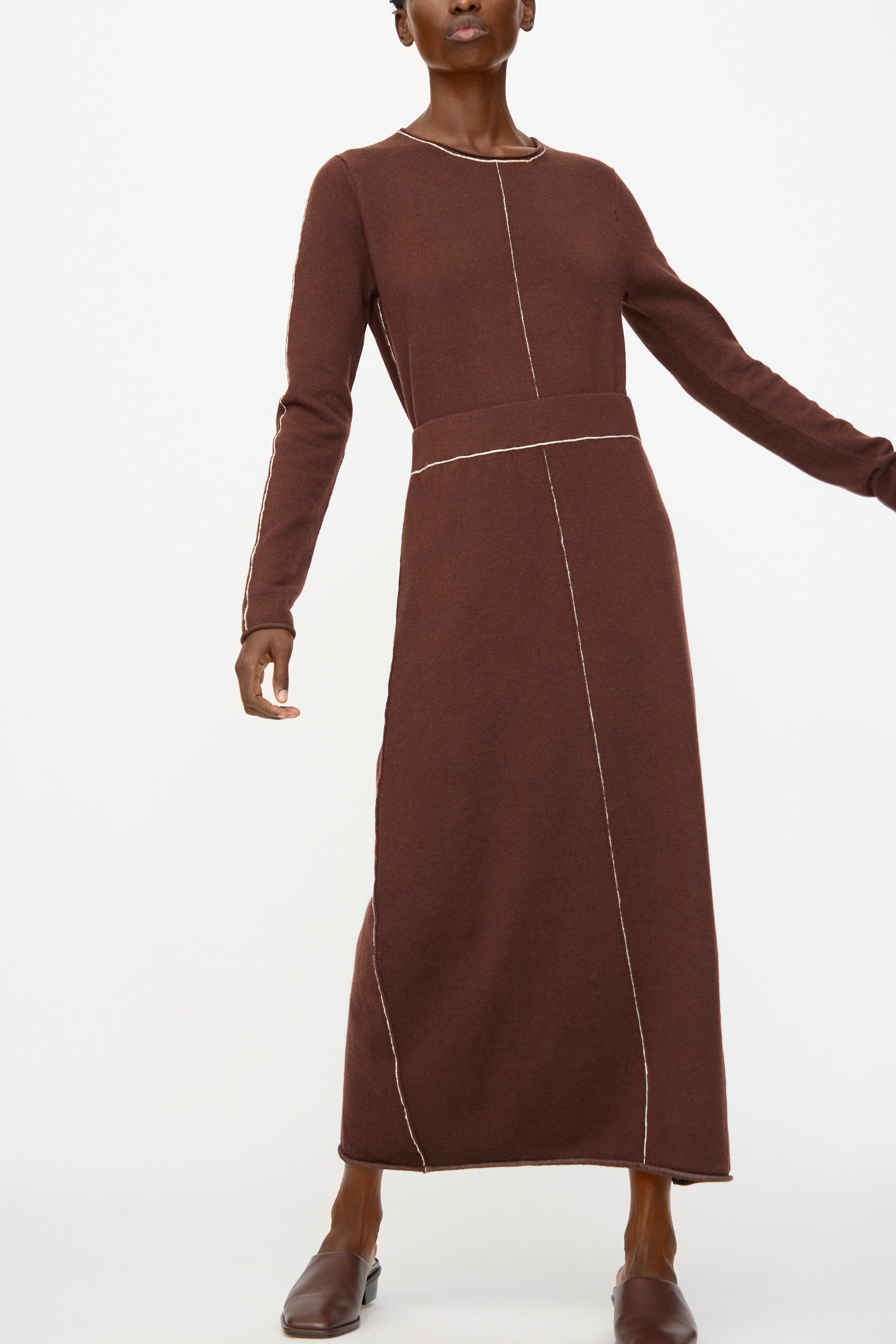 Model wears the Lauren Manoogian Stitch Skirt in Merlot—an ankle-length, long-sleeve brown dress with white seam details—against a plain white background.