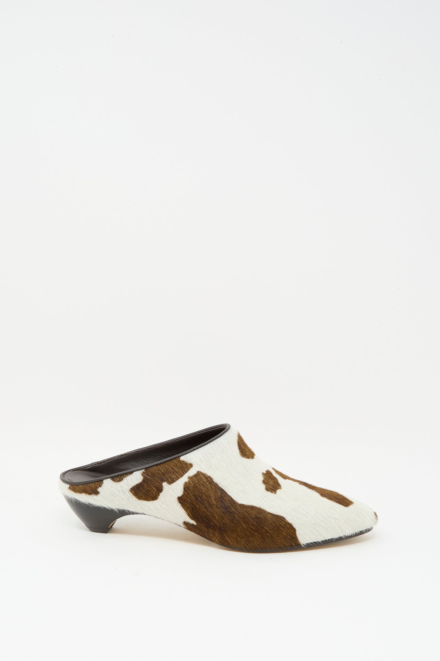 The Allegra Mule in Cow by Le Monde Beryl features a chic brown and white cow print in calf hair leather, finished with a sleek low black heel.