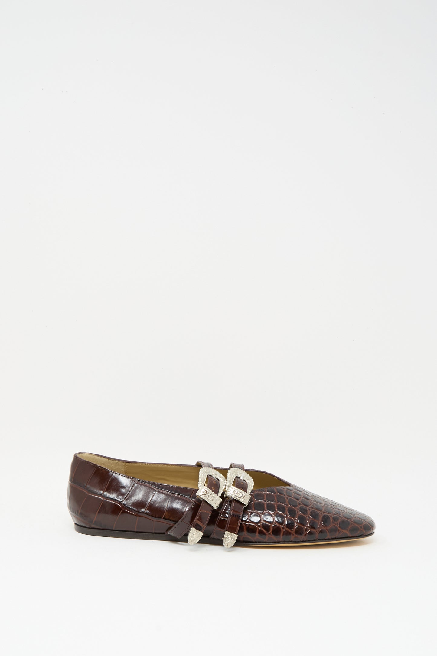 The Claudia Slipper in Coco Brown by Le Monde Beryl is a luxurious calf leather ballet flat with a crocodile pattern and two silver buckles, displayed in profile against a plain white background.