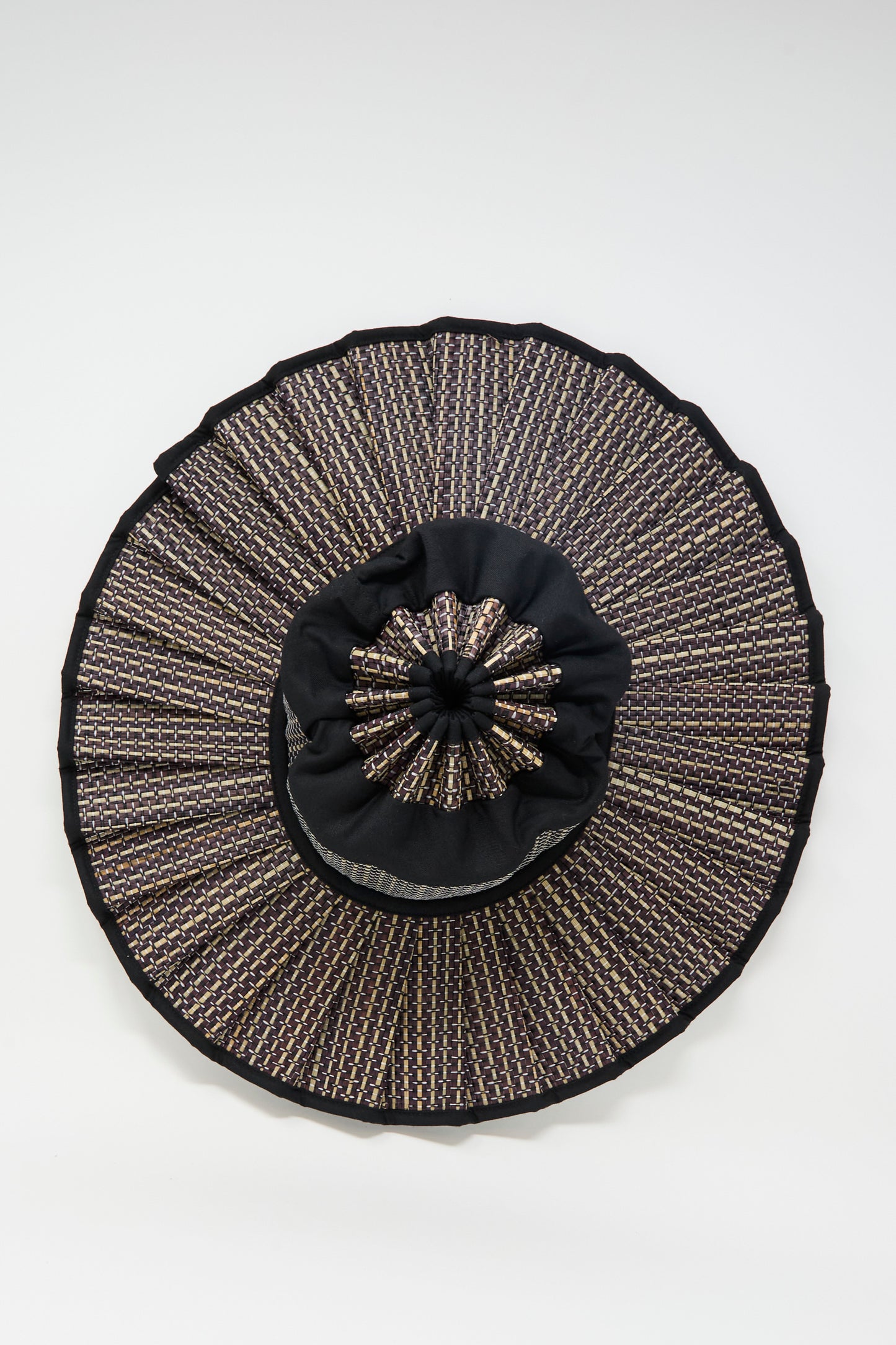 The Lorna Murray Melbourne Island Capri Maxi Hat is a round, black and gold sun hat woven from natural grass fibers with a pleated ruffle design, providing UPF 50+ sun protection. Shown against a plain white background.