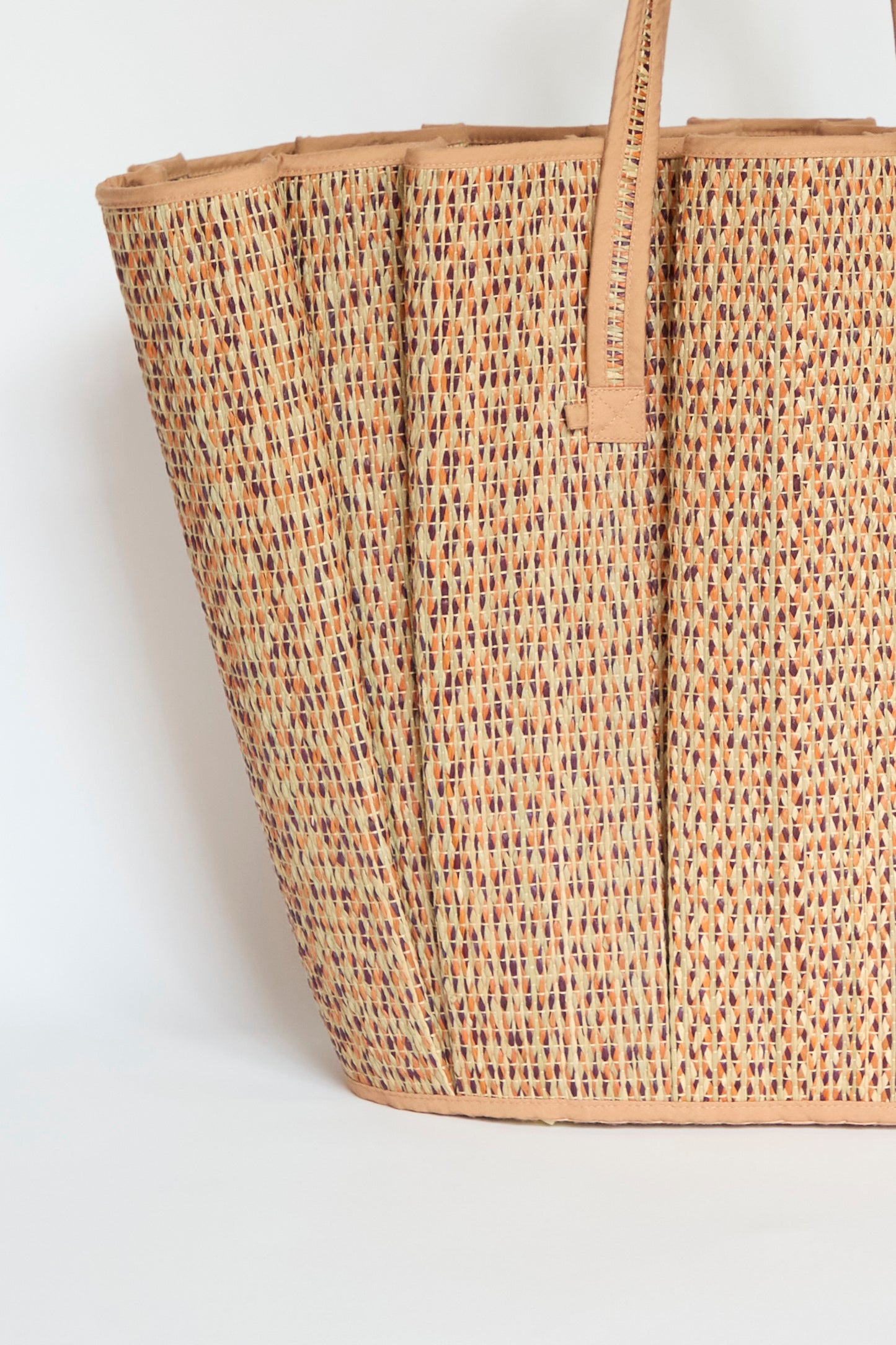 A close-up of the Lorna Murray Tropez Tote in Dawn, featuring a textured woven straw design, tan leather handles, and multicolored detailing, displayed against a plain white background.