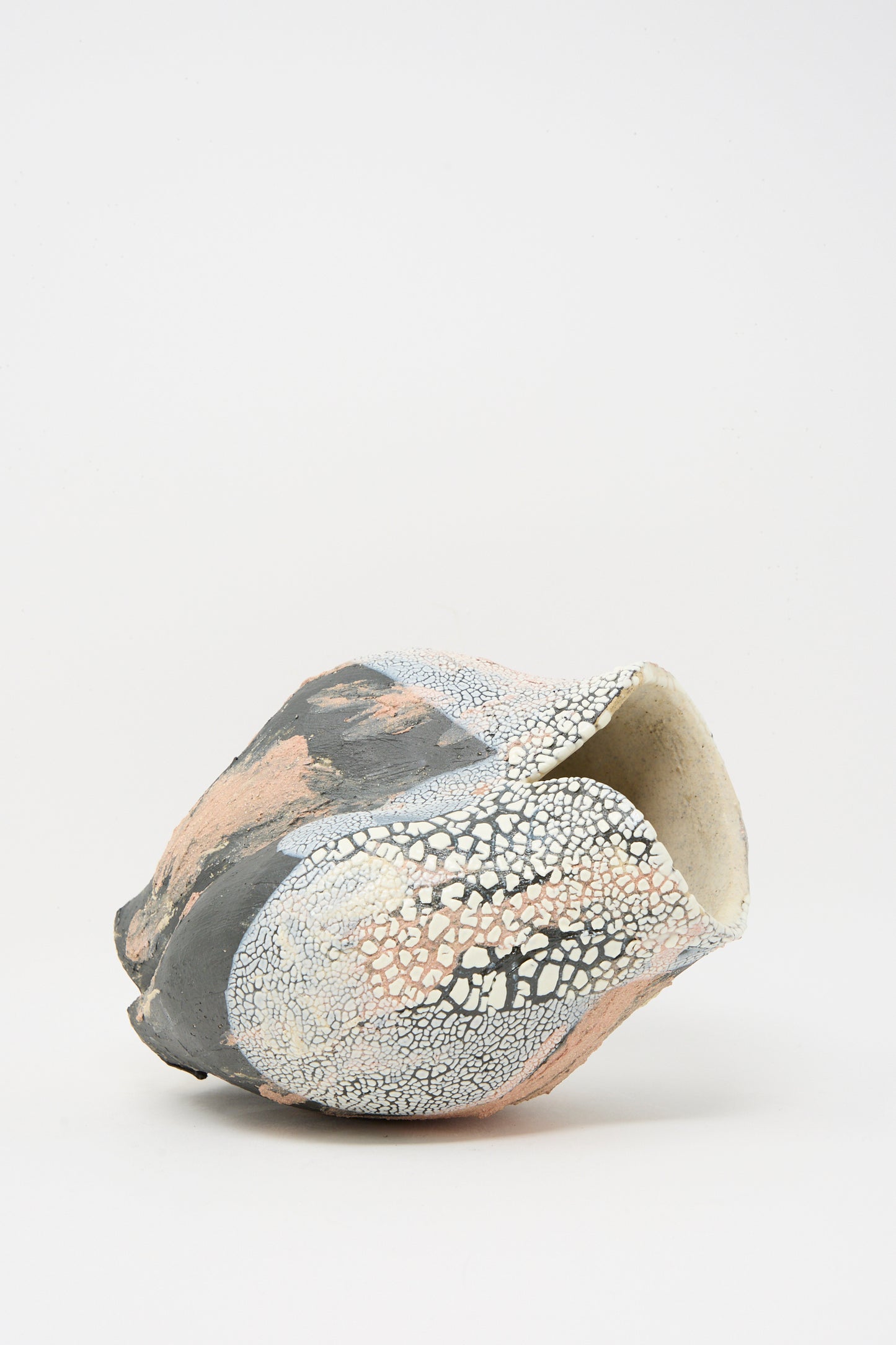 The Lost Quarry Medium Hand Built Textured Vessel in Black Pink Multi features an irregular ceramic form, sculptural clay details, and a cracked, textured surface in black, white, and pink against a plain white background.