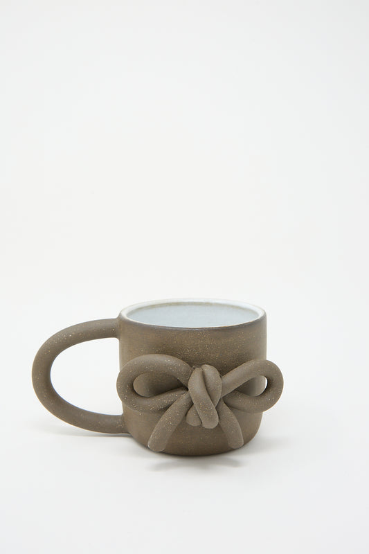 A hand-formed ceramic Mug with Bow in Black design on the handle, displayed against a plain white background by Lost Quarry.