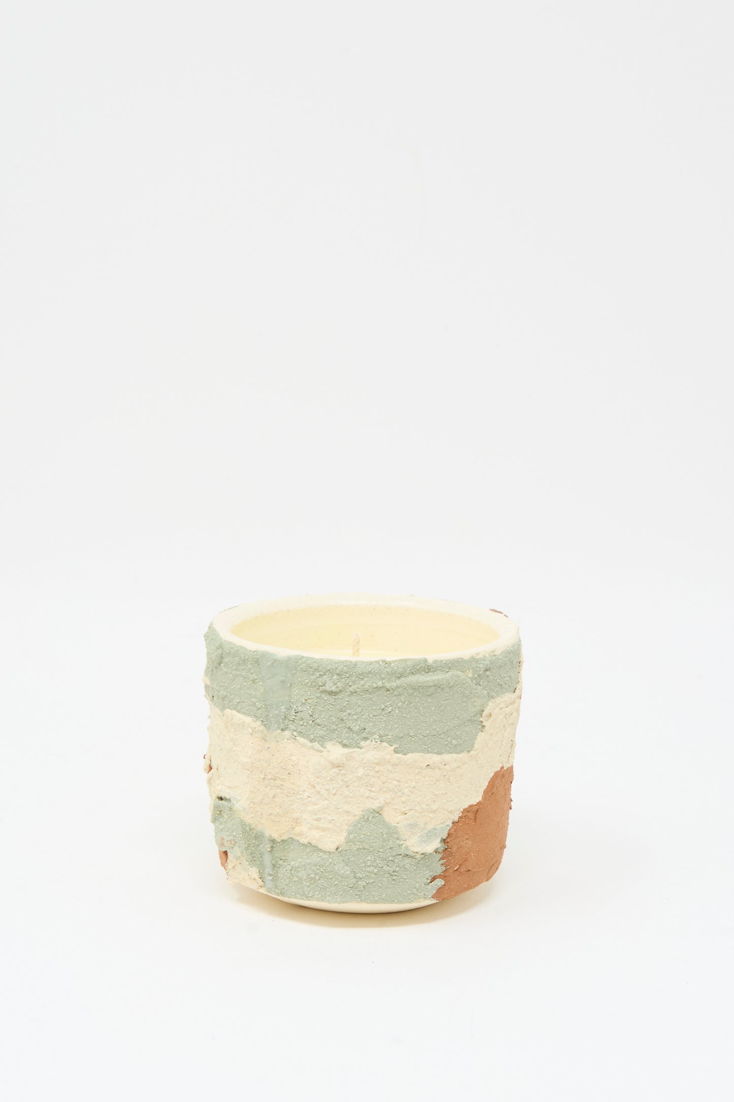 The Neroli Candle in Lime Terracotta Multi by Lost Quarry is a small, round scented candle housed in a textured, multicolored ceramic vessel with green, white, and brown sections, shown against a plain white background.