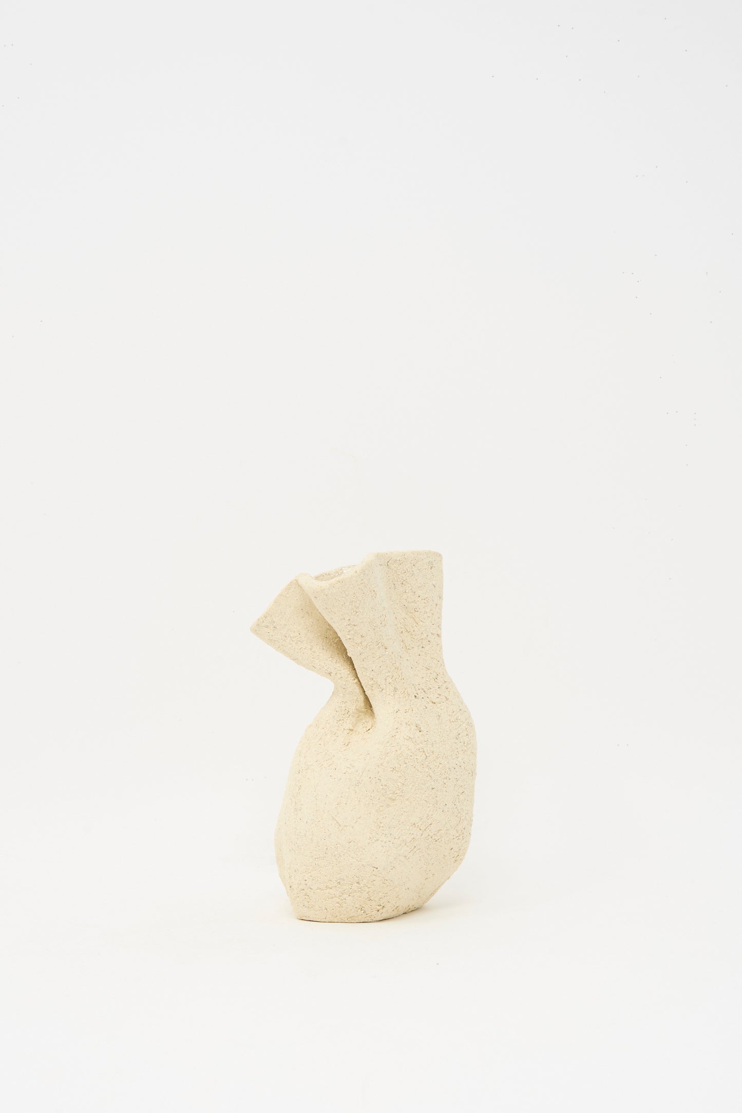 The Lost Quarry Textured Clay Folded Vessel I is a beige, irregularly shaped ceramic vase with a rough texture, made from white sculpture clay and displayed against a plain white background.