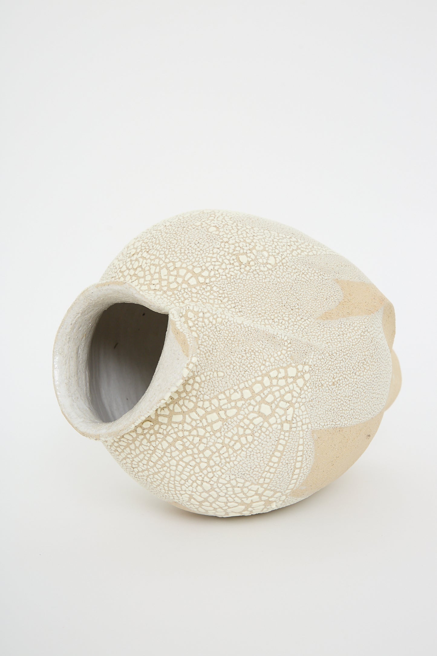 Lost Quarry's Vessel No. 741, made of white sculpture clay, features a textured beige and white ceramic design with a round body and curved opening, impeccably displayed on a plain white background.