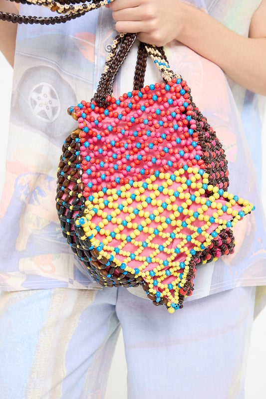 A woman is holding a colorful beaded Luna Del Pinal Assorted Beads Hectic Long Strap Bag in Multi Noise.