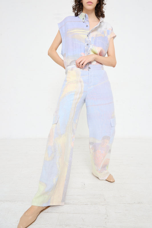 The model is wearing a colorful jumpsuit with cargo pockets, the Hemp Cargo Trouser in Oversized Digital Market Print by Luna Del Pinal.