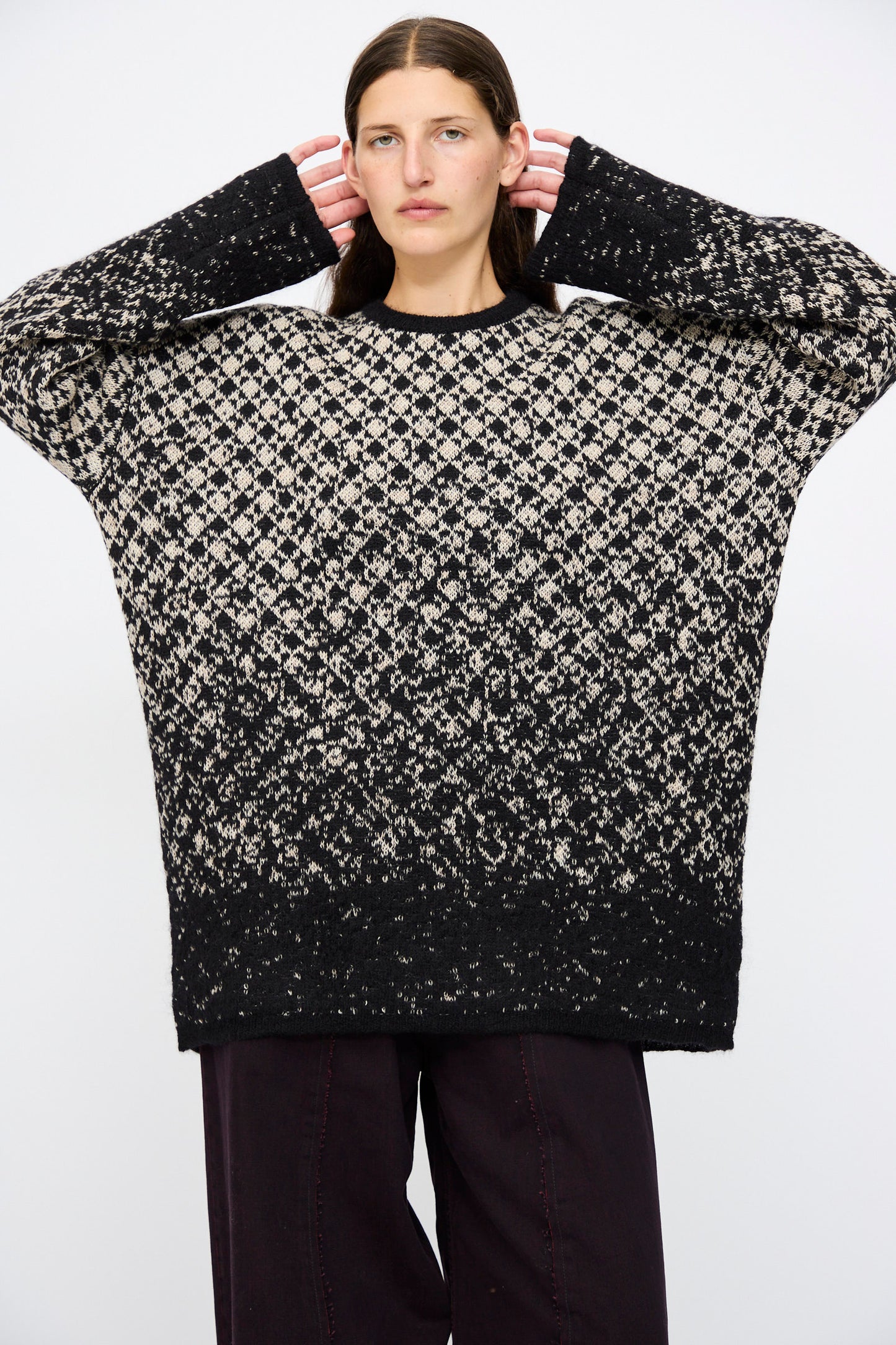 A person wears the MM6 Crewneck in Black and Beige with dark pants, standing against a plain white background.