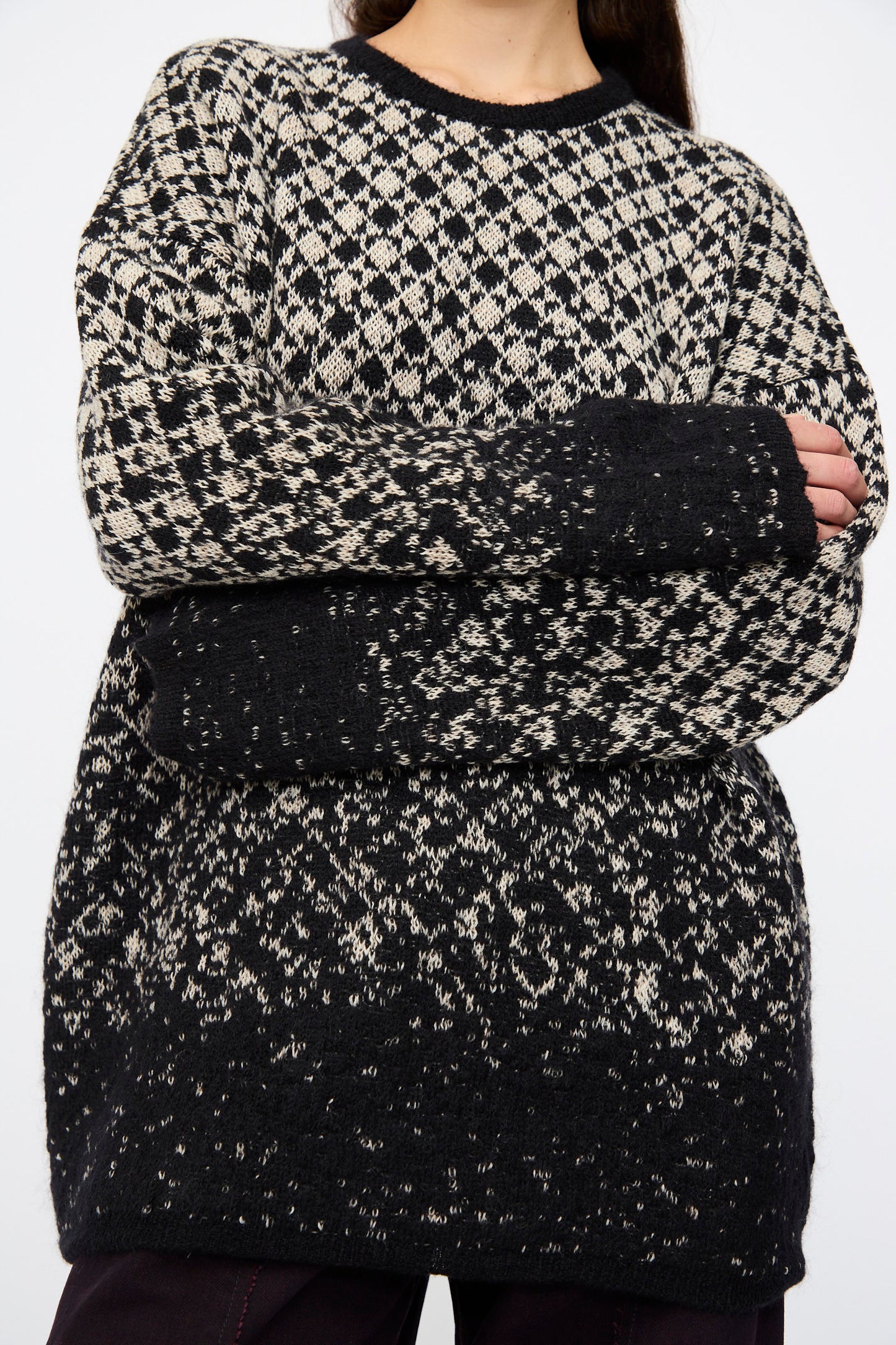 Model wears the MM6 Crewneck in Black and Beige, featuring an oversized fit and abstract pattern, with long sleeves crossed over their chest; photo shows shoulders to mid-thigh.