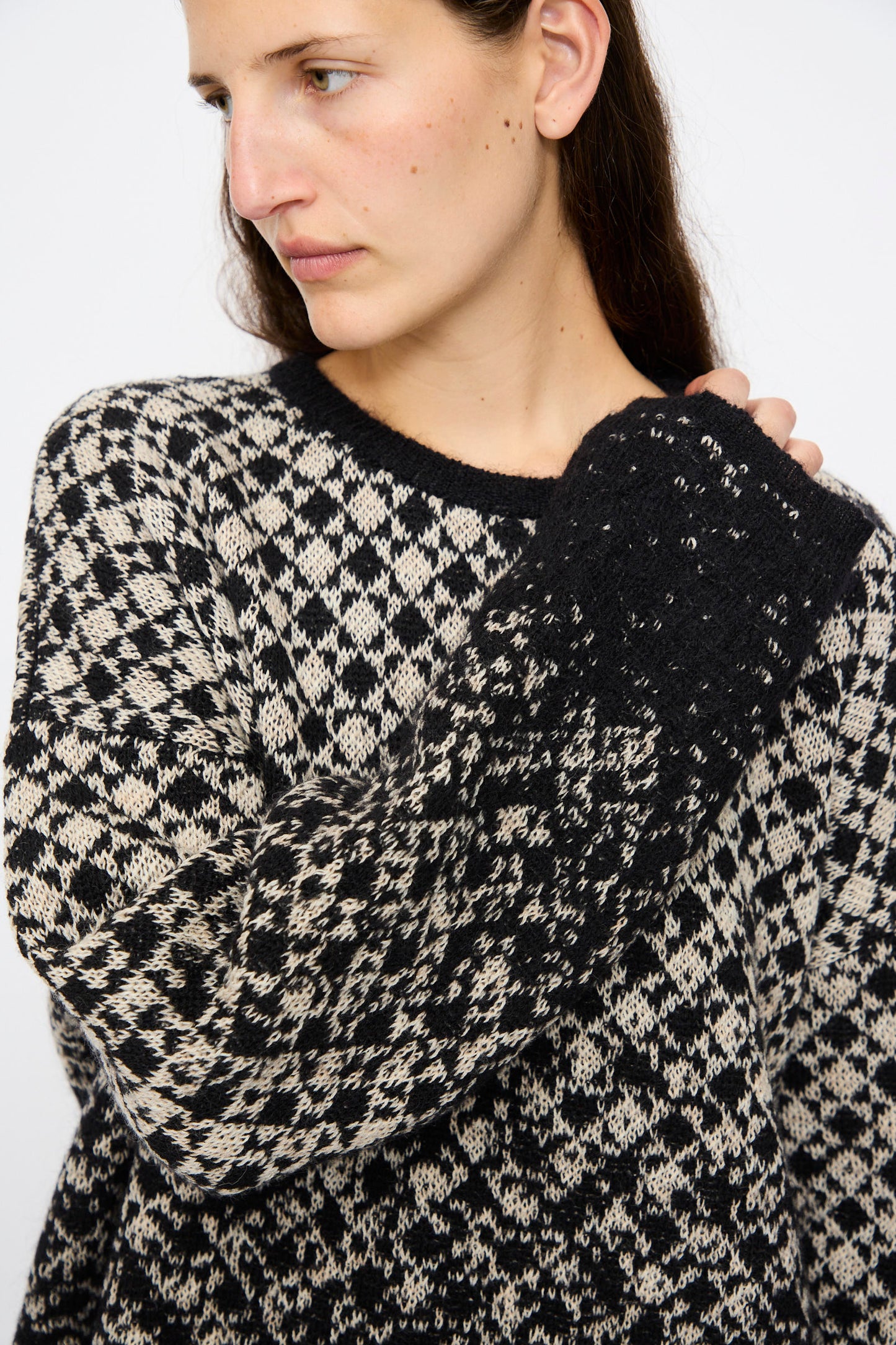 A person wearing the MM6 Crewneck in Black and Beige with an abstract pattern looks to the side against a plain background.