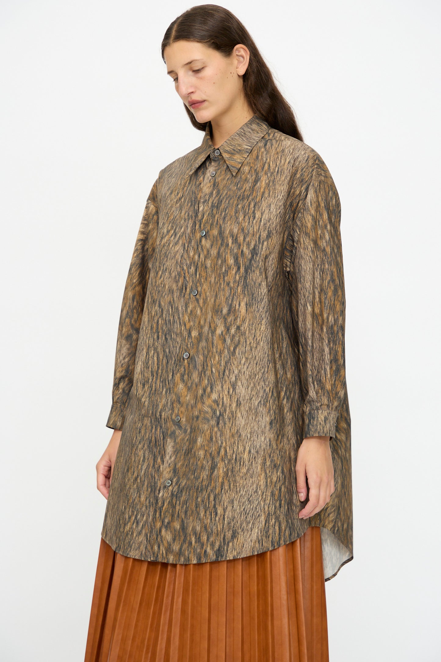 A person wears the MM6 Dress in Brown, featuring a long, loose fit with an animal print and textured brown pattern, standing against a plain background.
