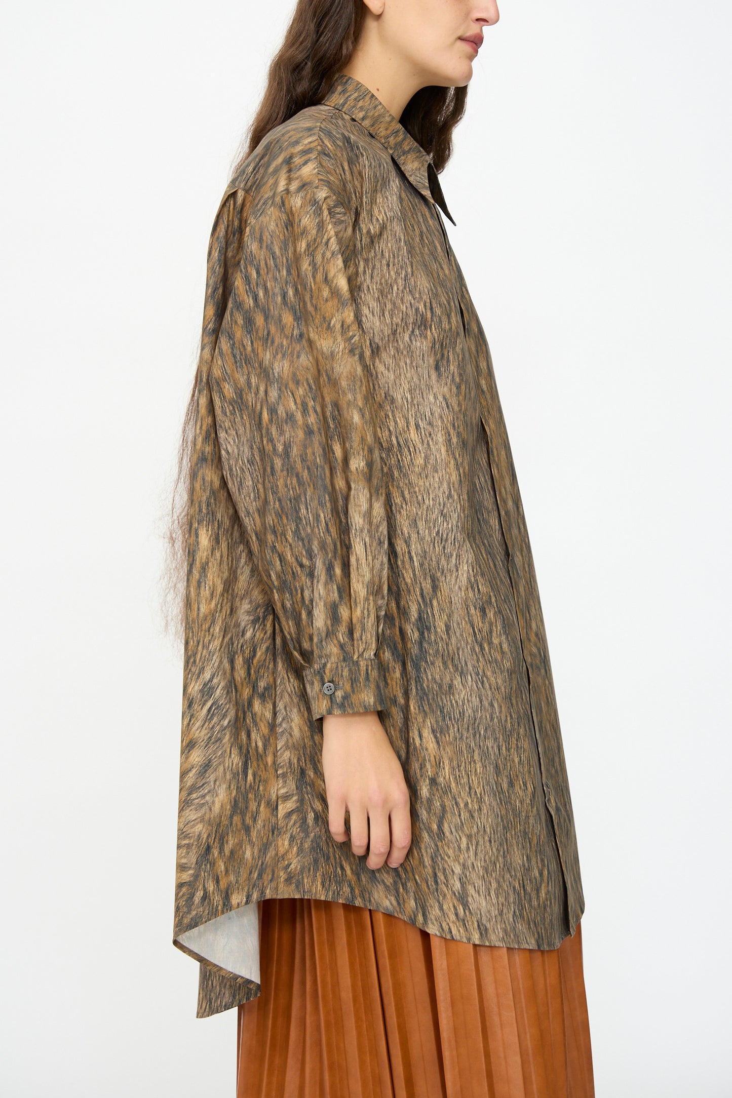 A person is shown from the side wearing the MM6 Dress in Brown, featuring an animal print, pointed collar, and pleated skirt—showcasing chic Italian craftsmanship against a plain background.