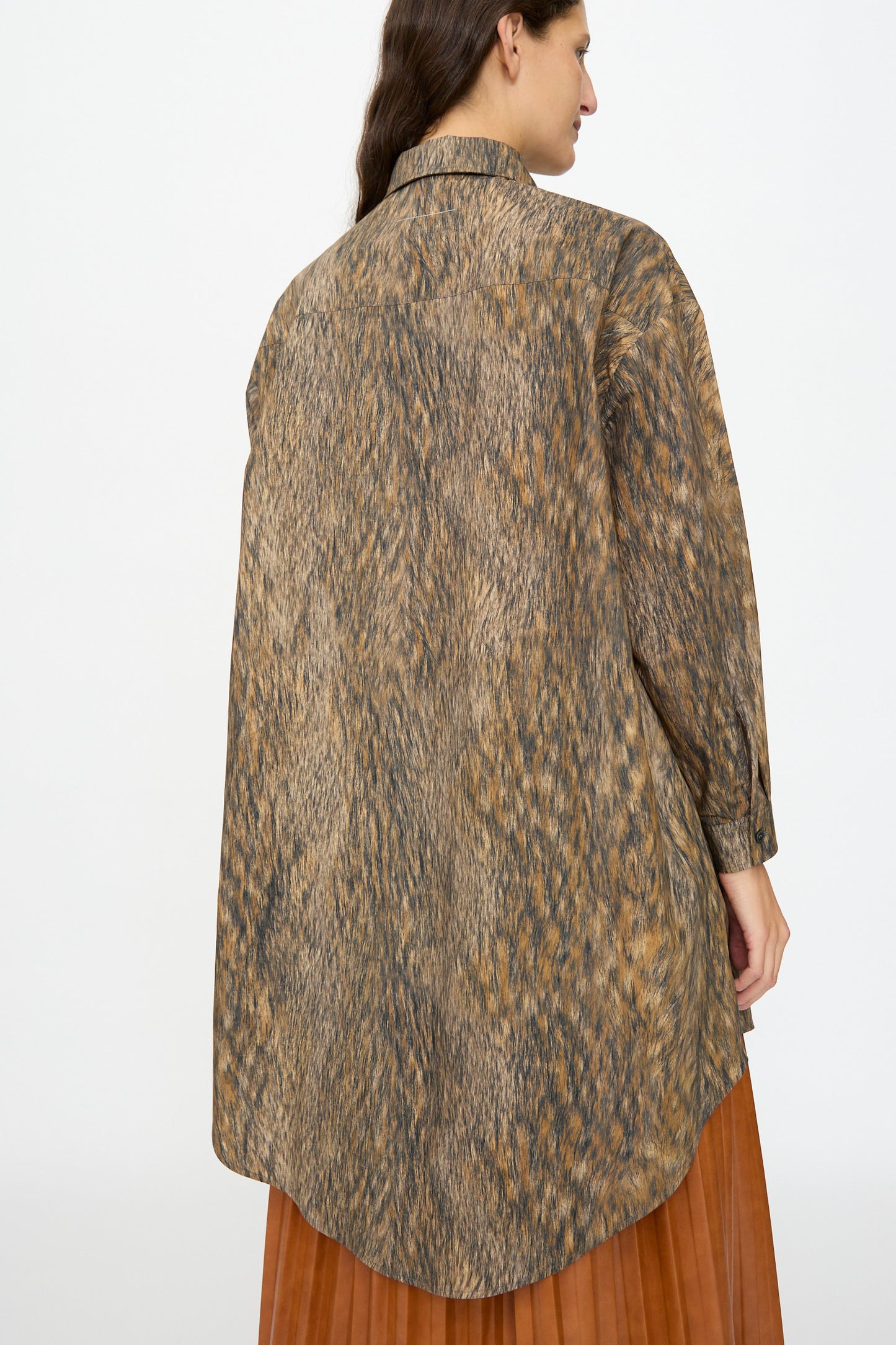 A woman is shown from the back wearing the MM6 Dress in Brown, a loose, long-sleeved animal print shirt dress with a curved hem.