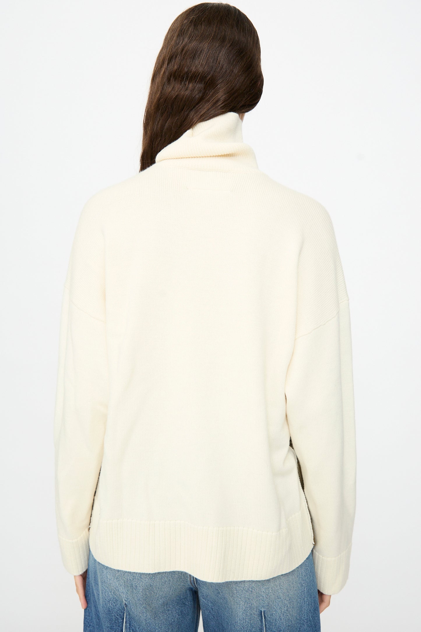 A person with long brown hair is shown from the back against a plain white background, wearing the MM6 Pullover in Off White-khaki paired with blue jeans.