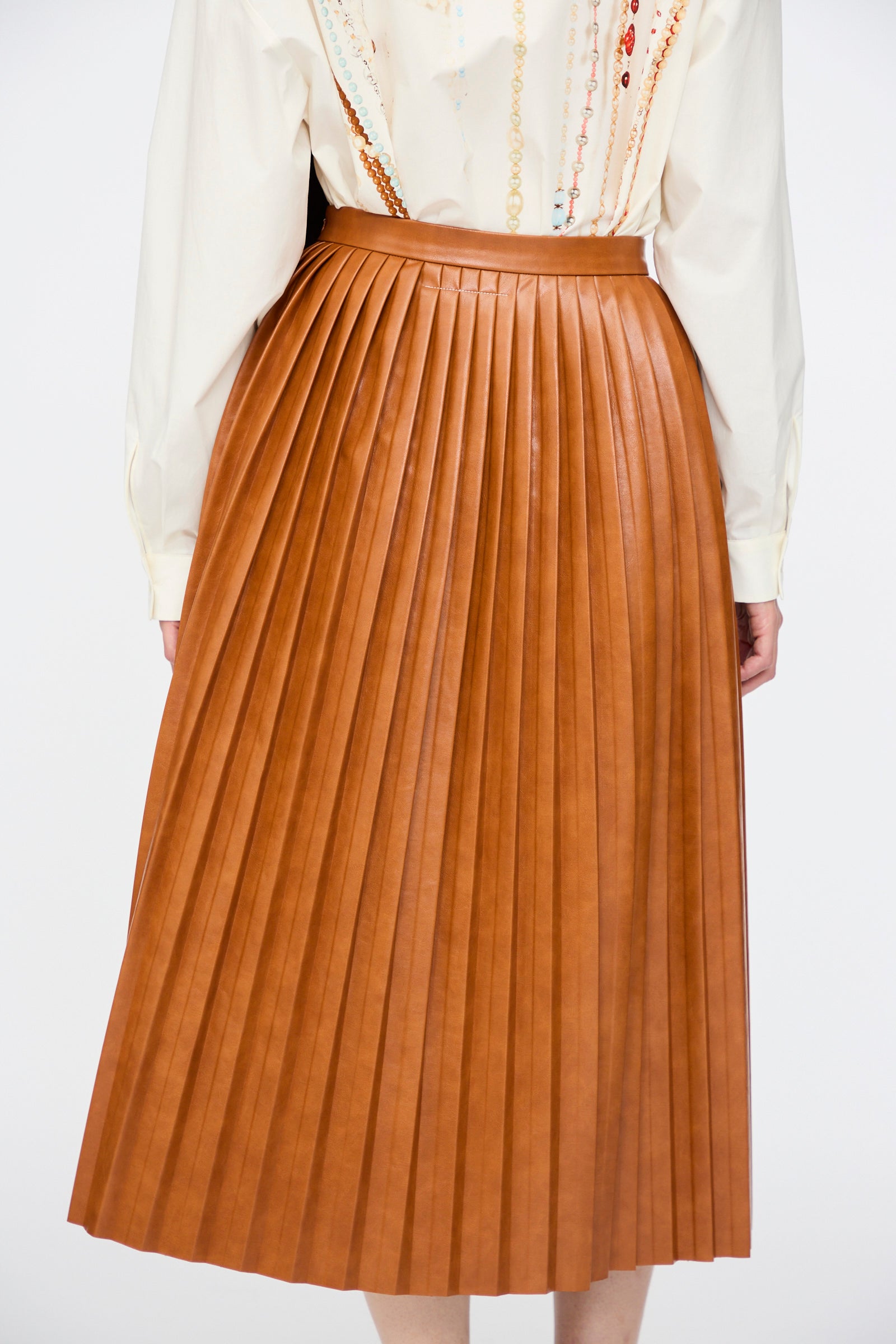 A person wearing a cream long-sleeve shirt and the MM6 Skirt in Caramel, photographed from the back against a plain background.