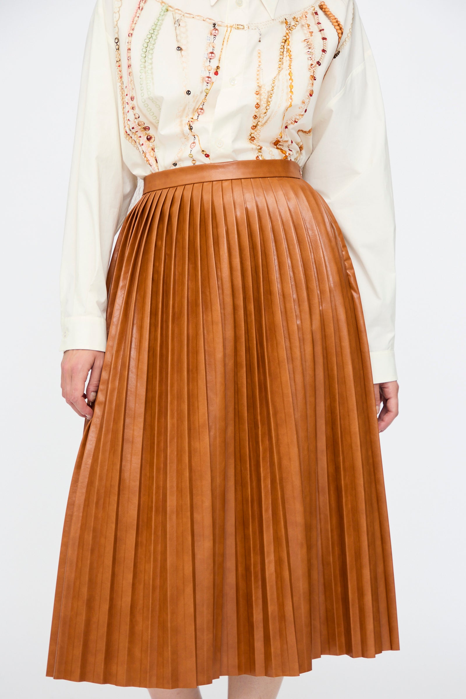 A person wearing a white patterned long-sleeve blouse paired with the MM6 Skirt in Caramel.
