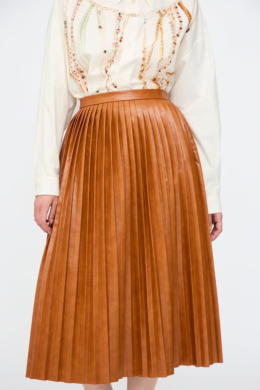 A person wearing a white patterned long-sleeve blouse paired with the MM6 Skirt in Caramel.