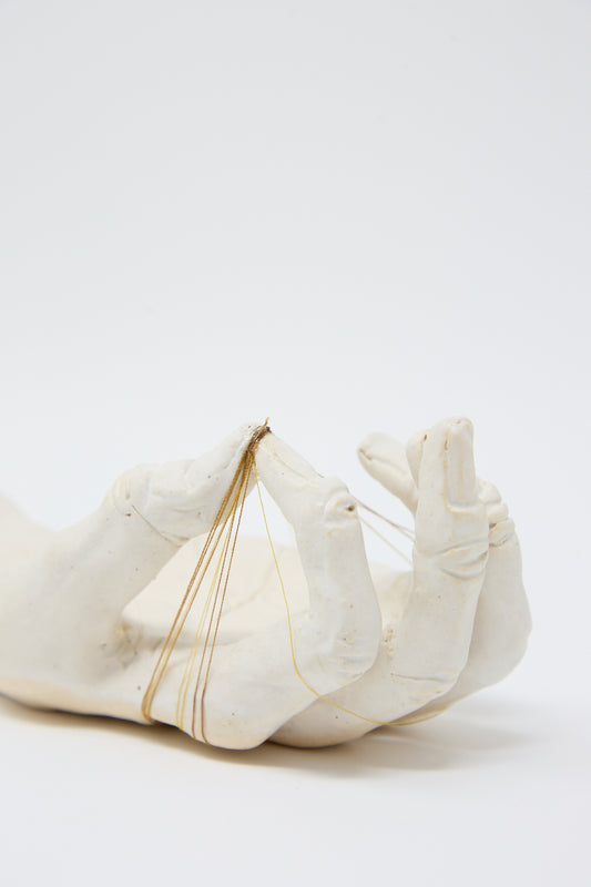 The Monty J Ceramic Hand Sculpture with Brown Thread, handmade in Brooklyn, features delicate golden and brown thread details strung between the fingers against a plain white background.