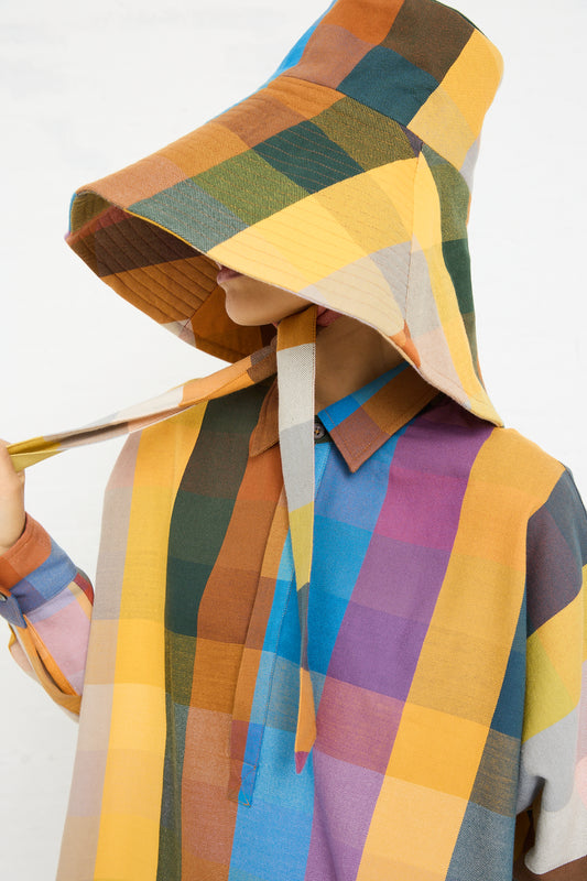 A person wearing a colorful checkered Marrakshi Life Hat in Multi Check with the hood up, covering most of their face.