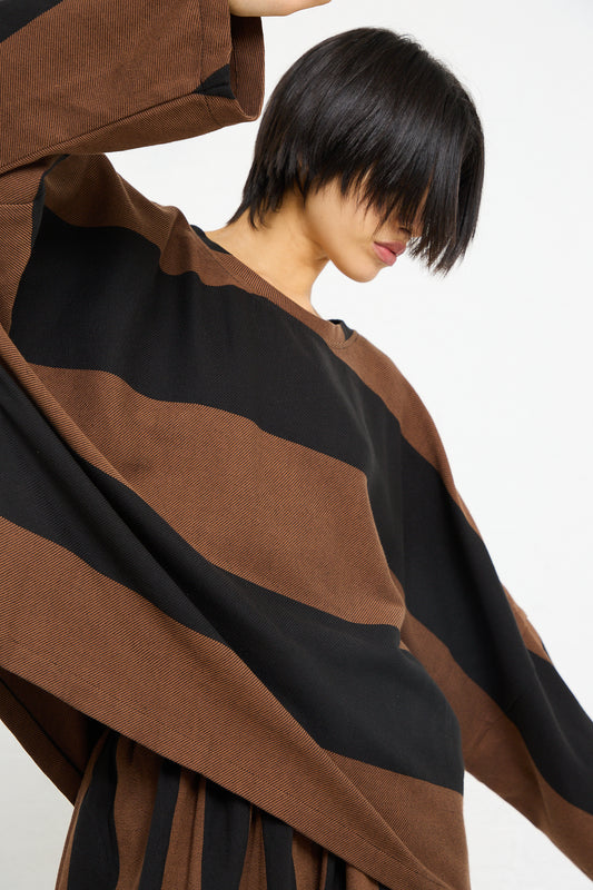 Woman posing in a Marrakshi Life Twill Sweater in Black and Brown Stripe with a modern haircut.