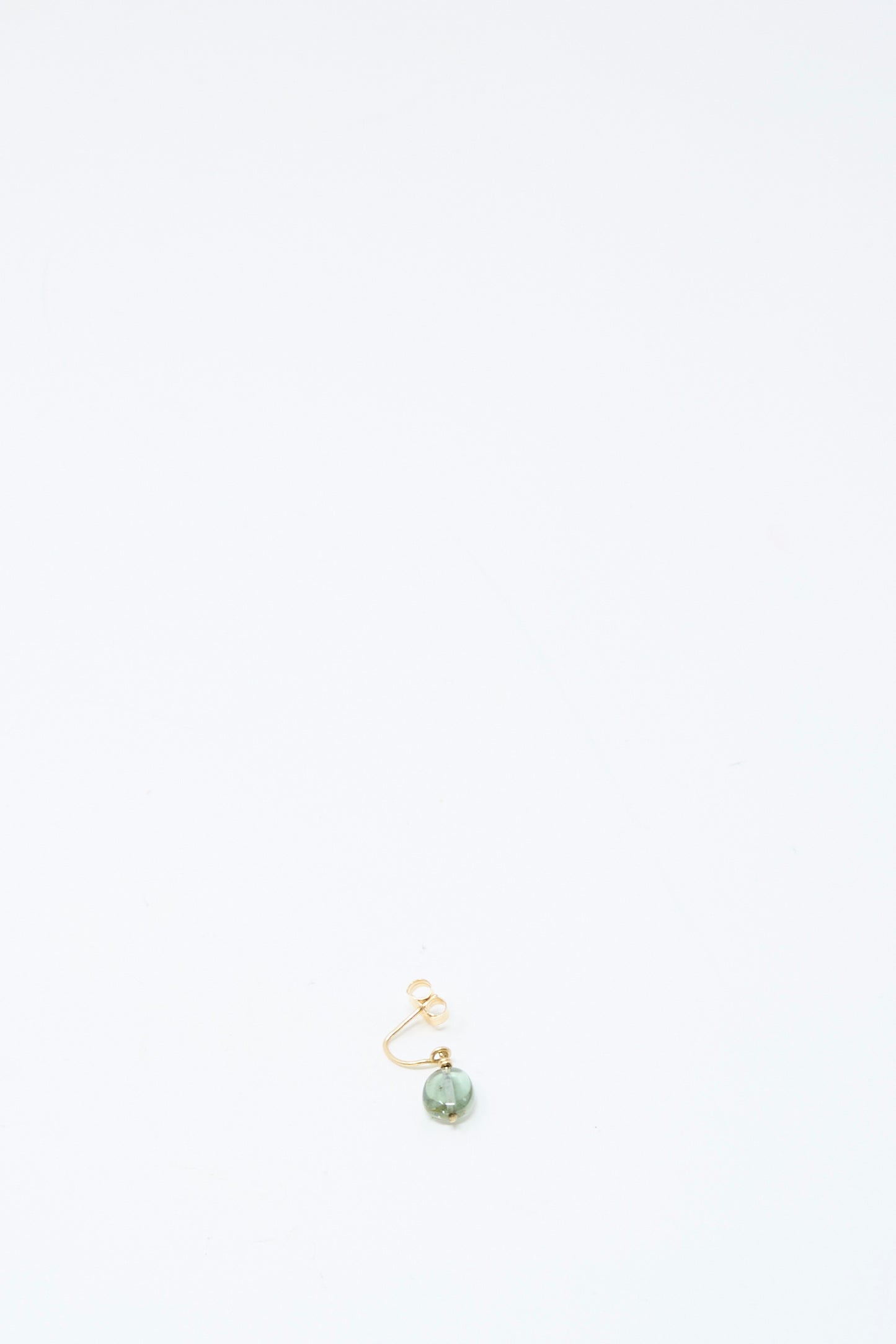 The Mary MacGill 14K Crescent Charm Single Earring in Round Tourmaline is a handmade gold hoop featuring a green tourmaline bead, centered near the bottom of a plain white background.