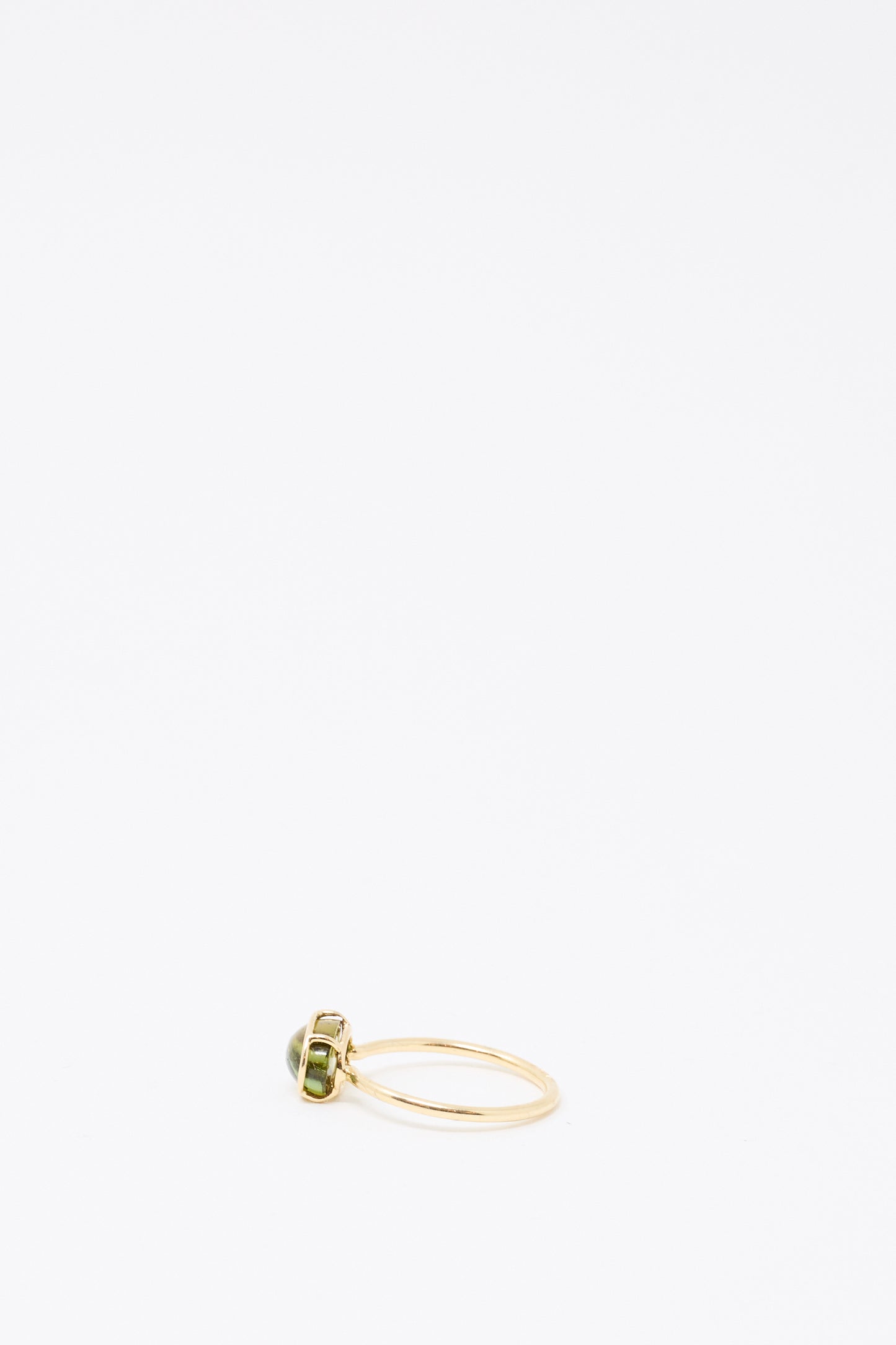 The Mary MacGill 14K Floating Ring in Petite Green Tourmaline showcases a handmade gold band with an oval green tourmaline centerpiece, displayed on a simple white background.