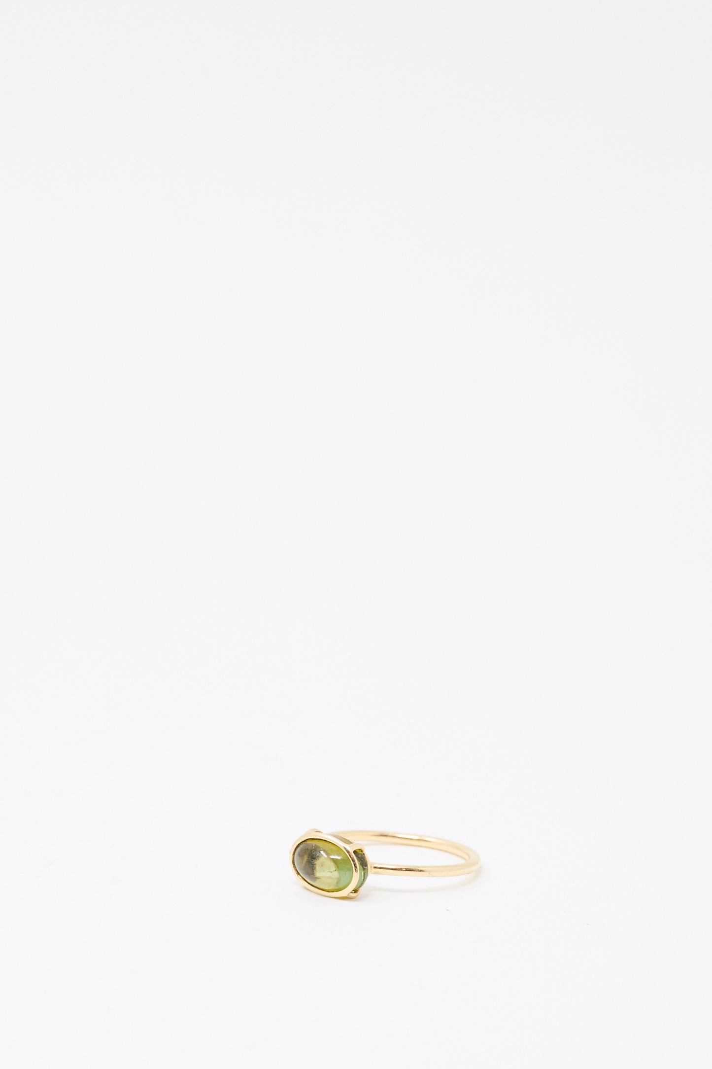 The Mary MacGill 14K Floating Ring in Petite Green Tourmaline, a handmade gold ring with an oval green tourmaline gemstone, is displayed on a white background.