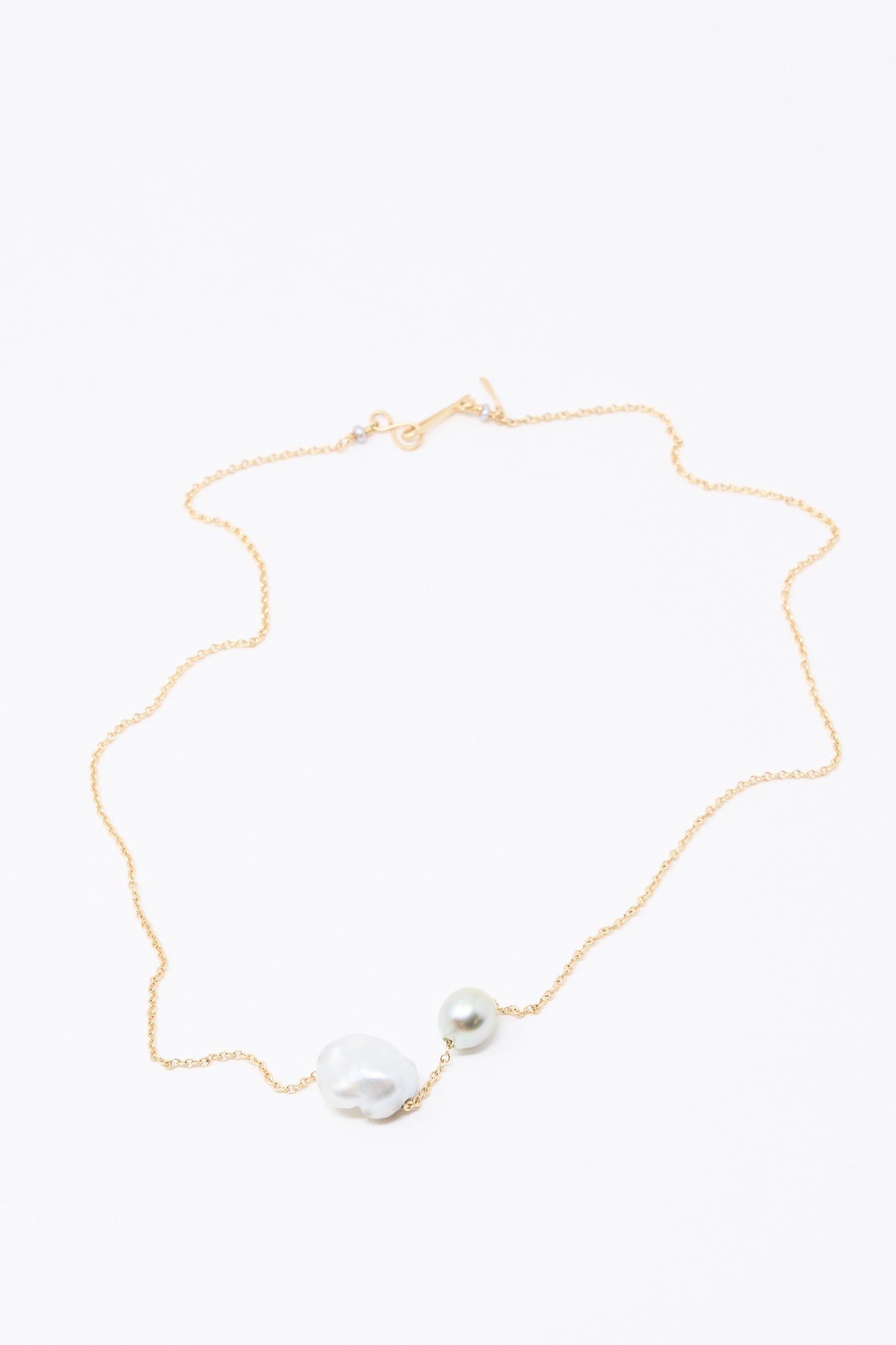 The Mary MacGill 14K Mermaids Purse Necklace features a Keshi pearl with an irregular shape and a perfectly round Tahitian pearl, elegantly displayed on a white background.