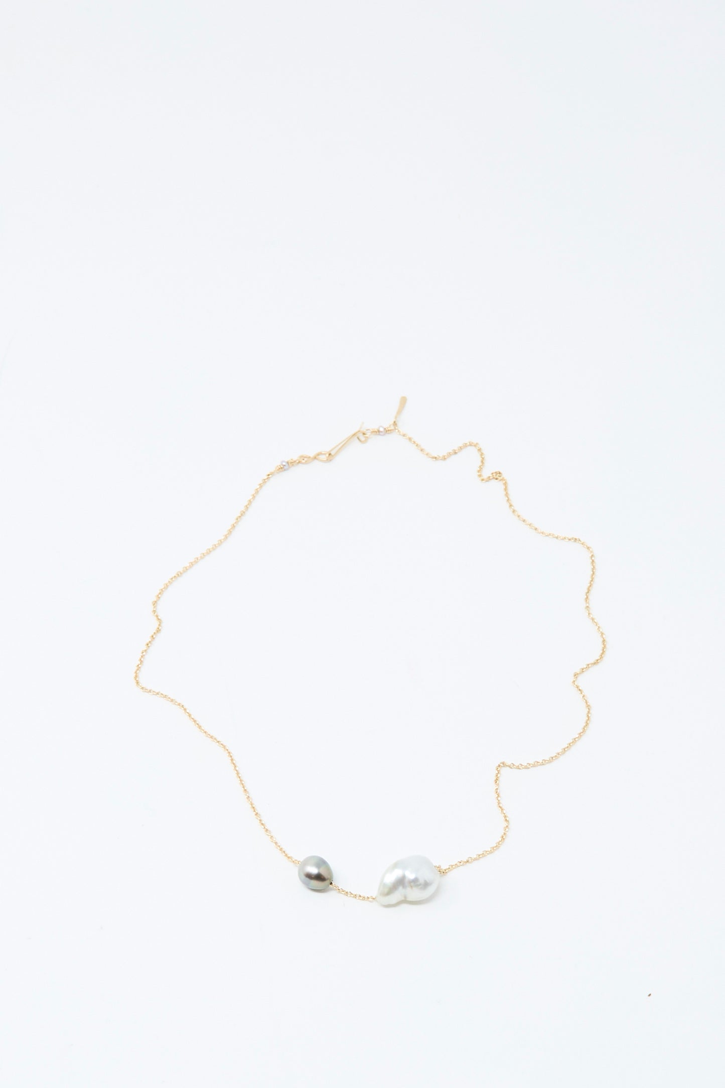 The Mary MacGill 14K Necklace in White Keshi and Silver Tahitian Pearl features a delicate gold chain with one small round silver bead and one larger, irregular bead, and shown on a white background.