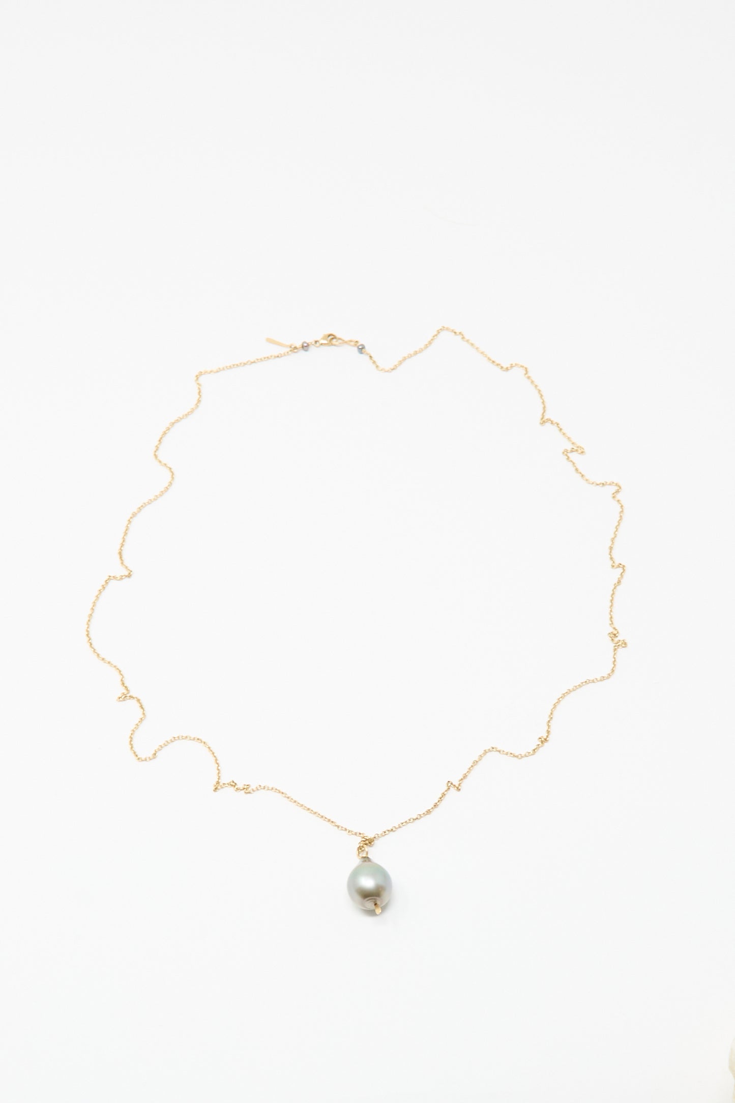 The Mary MacGill 14K Tahitian Pearl Drop Necklace in Charcoal Silver features a single round pearl on a delicate gold chain, handmade and displayed on a white background.