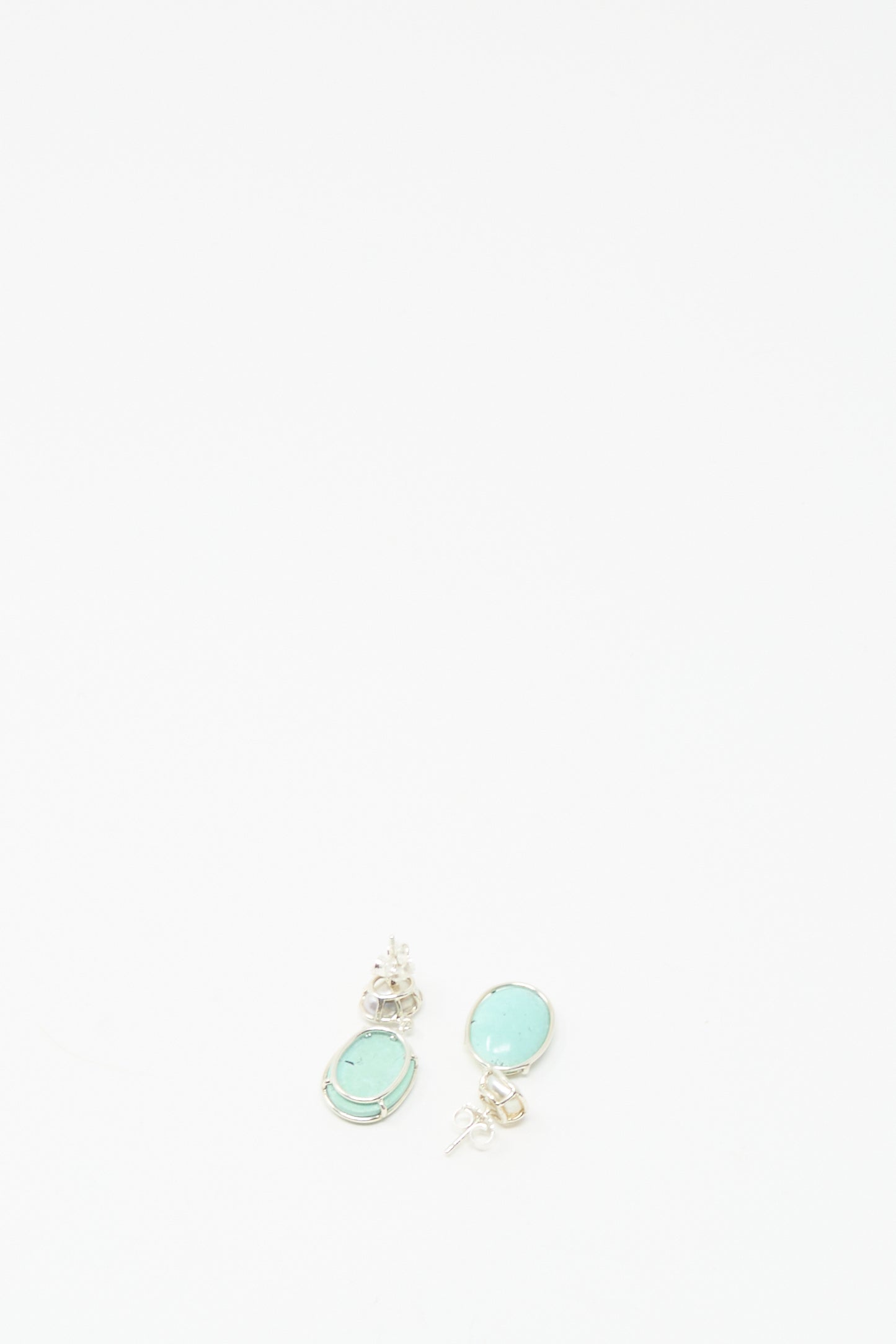 A pair of Double Stone Drop Earrings by Mary MacGill, featuring small turquoise and Keshi pearl stones, shown near the bottom center on a white background.