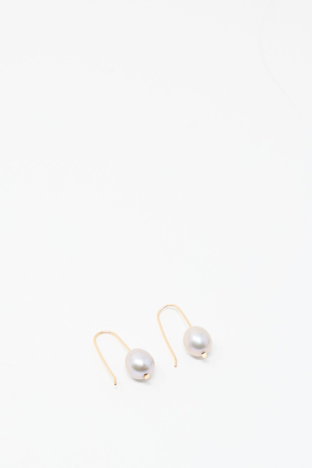 A pair of Mary MacGill Petite Baroque Pearl Drop Earrings in Silver, featuring a single baroque pearl, displayed on a plain white background.