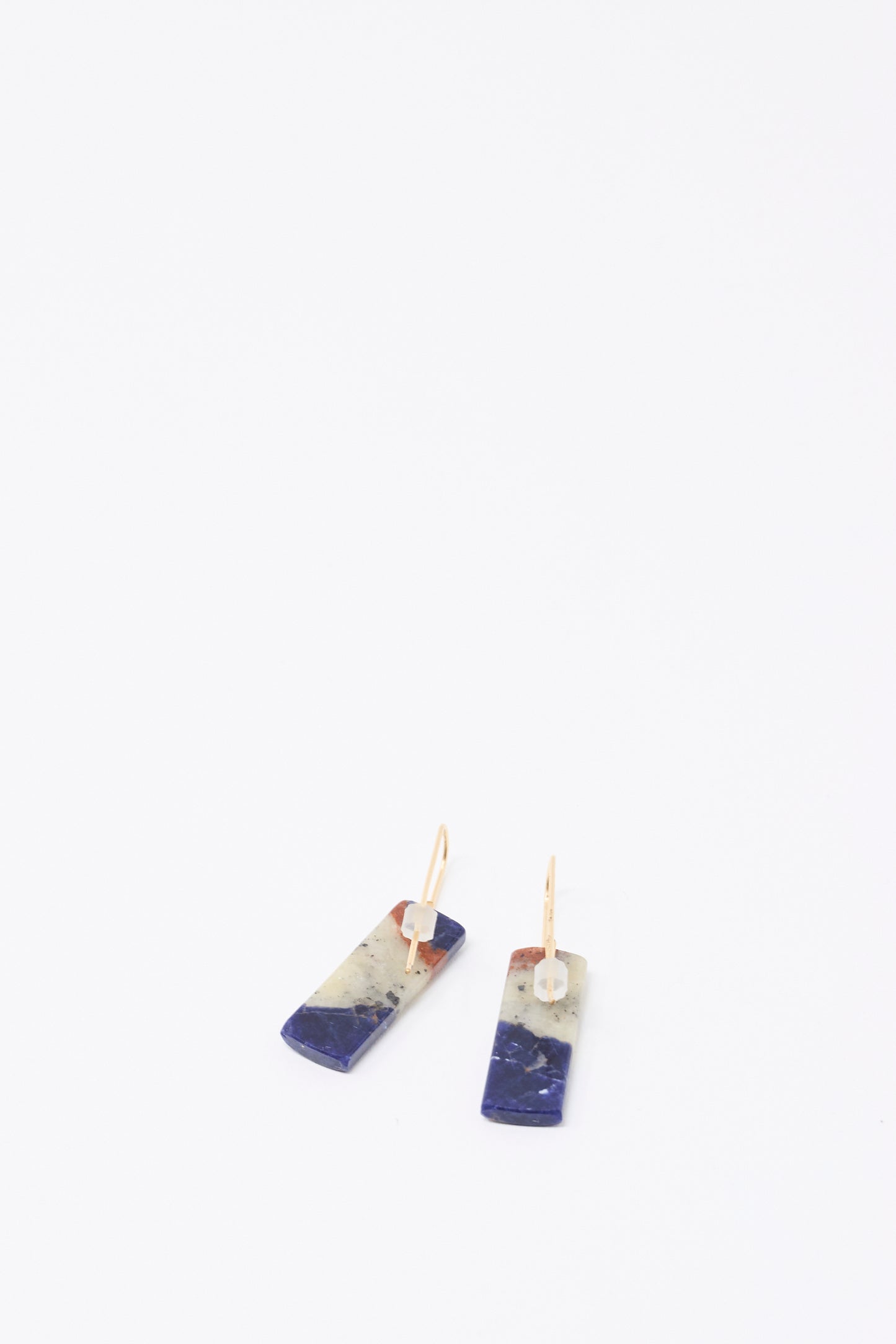 Mary MacGill Stone Drop Earrings in Sodalite feature handmade rectangular blue and white marbled stones with gold hooks, shown on a white background.