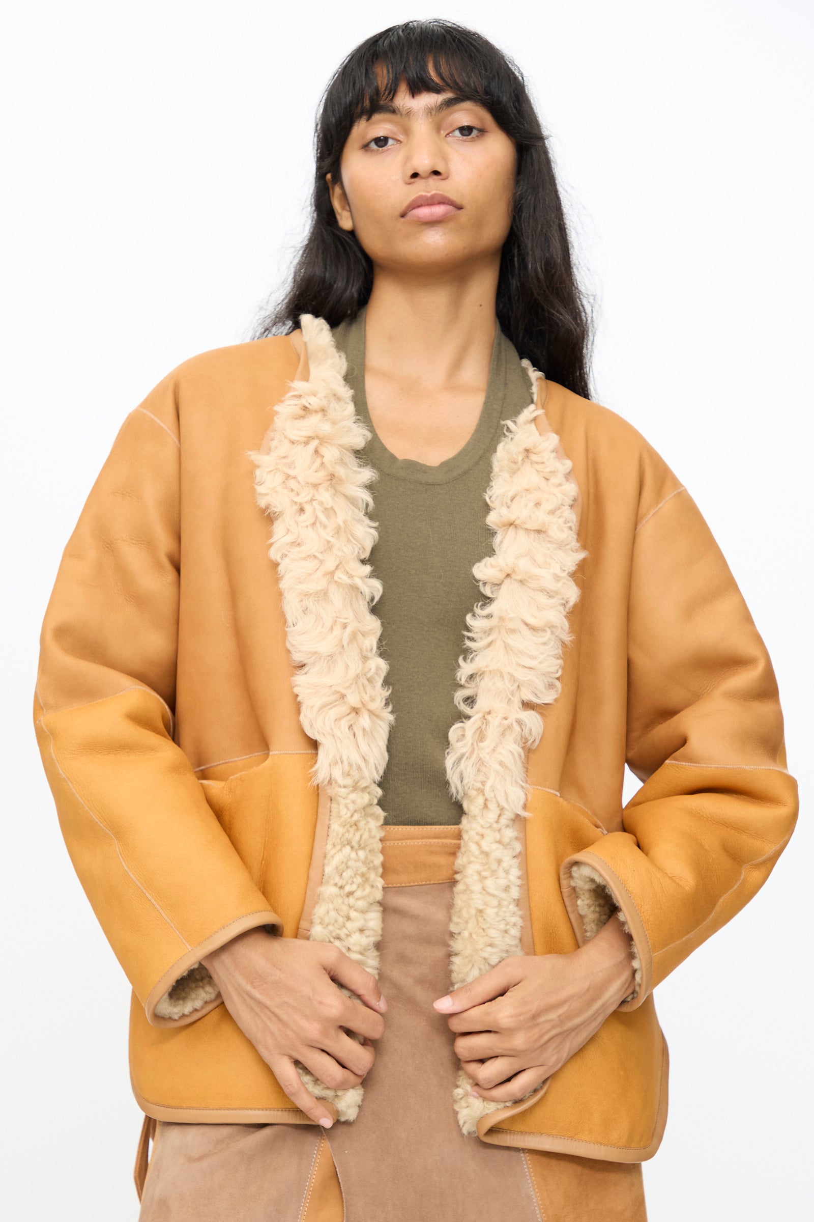 A person wears the Milena Silvano Pyramid Robe in Oat over an olive green top and tan pants, standing against a plain white background.