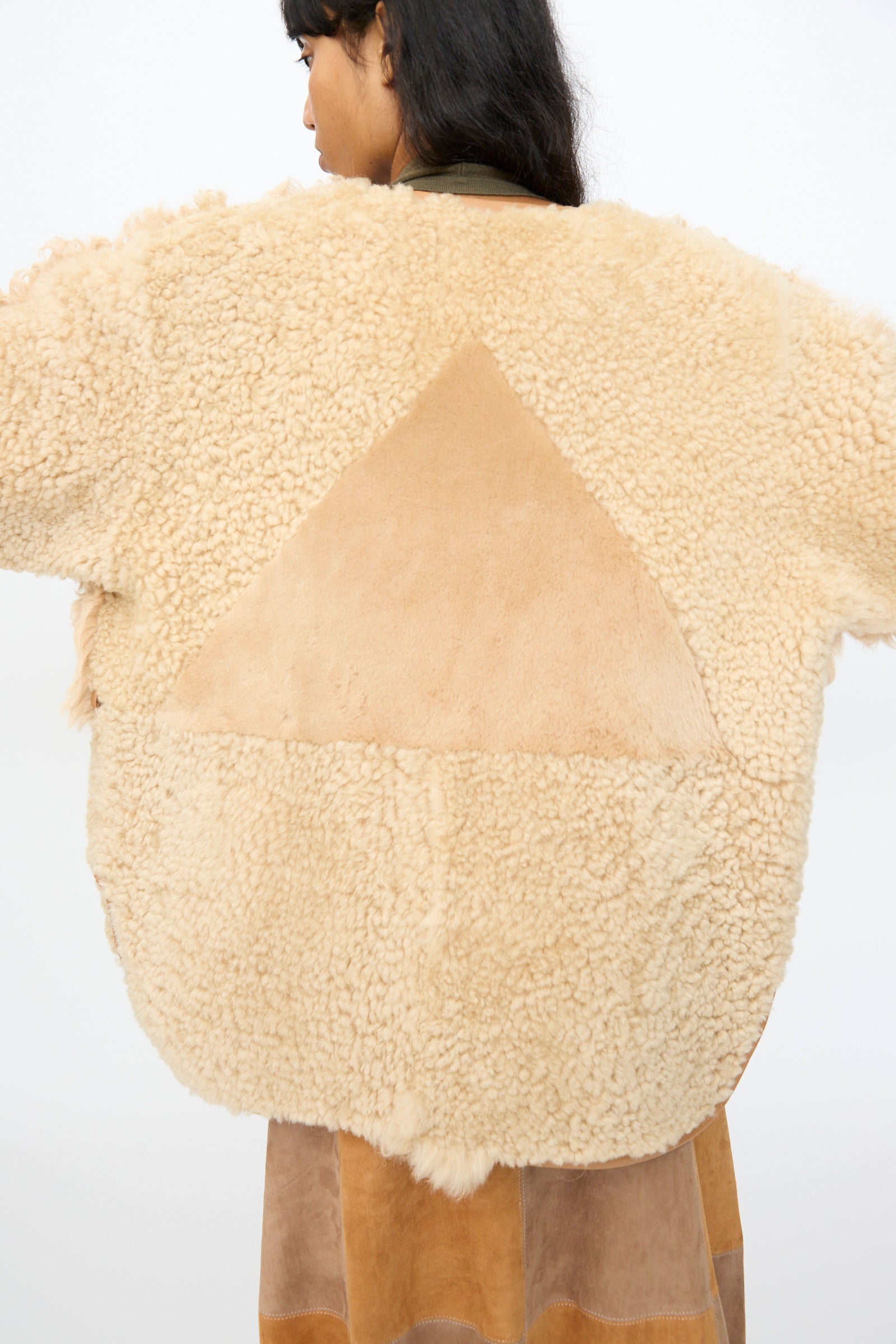 A person wearing the Milena Silvano Pyramid Robe in Oat, featuring a large tan suede triangle patch on the back, photographed from behind.