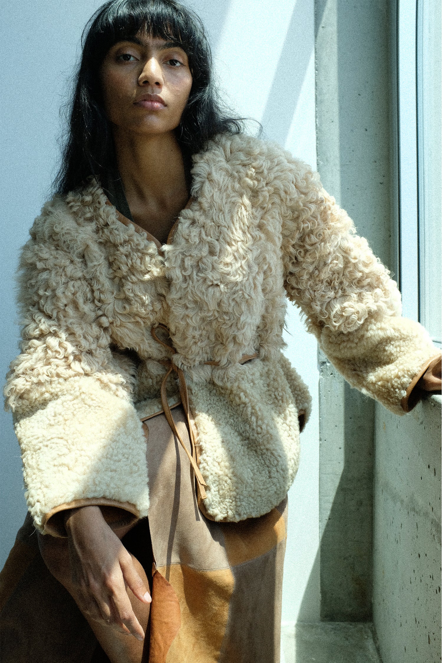 Woman wearing a sheepskin coat by Milena Silvano in a studio.