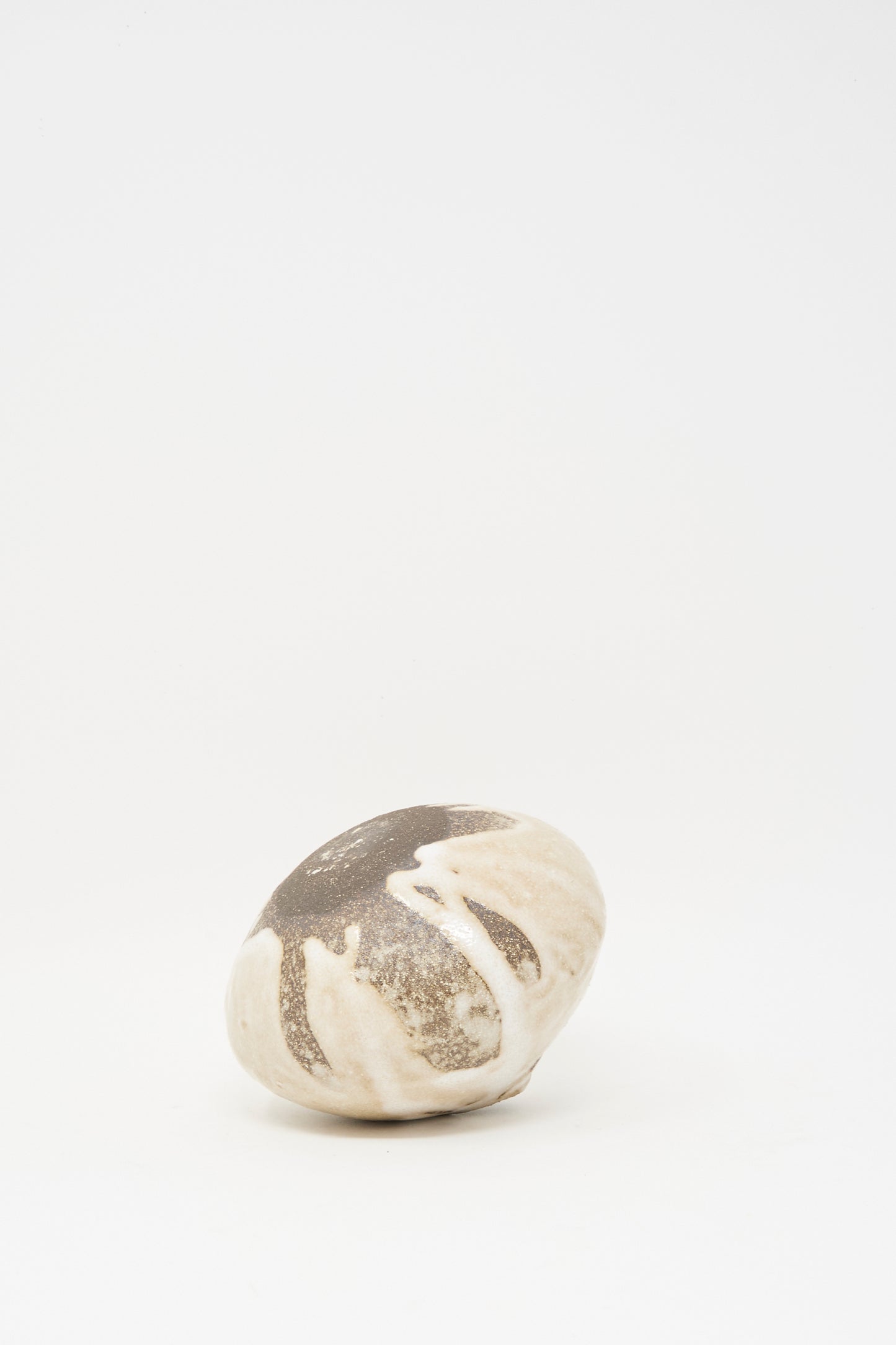The Glazed Stoneware Mini Moon Bud Vase by MONDAYS features a round, smooth surface with beige and dark brown marbled patterns, resembling artisanal textured stoneware vases, displayed on a plain white background.
