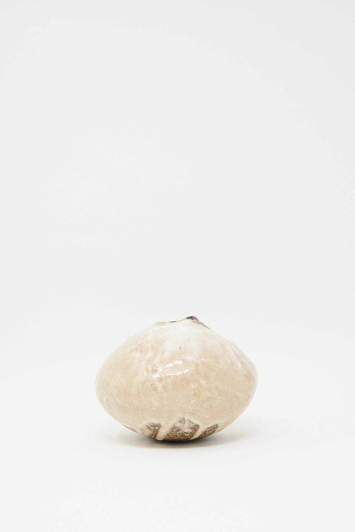 The MONDAYS Glazed Stoneware Mini Moon Bud Vase, featuring a single round beige form with a narrow opening, is centered on a plain white background, highlighting the elegance of handcrafted design.