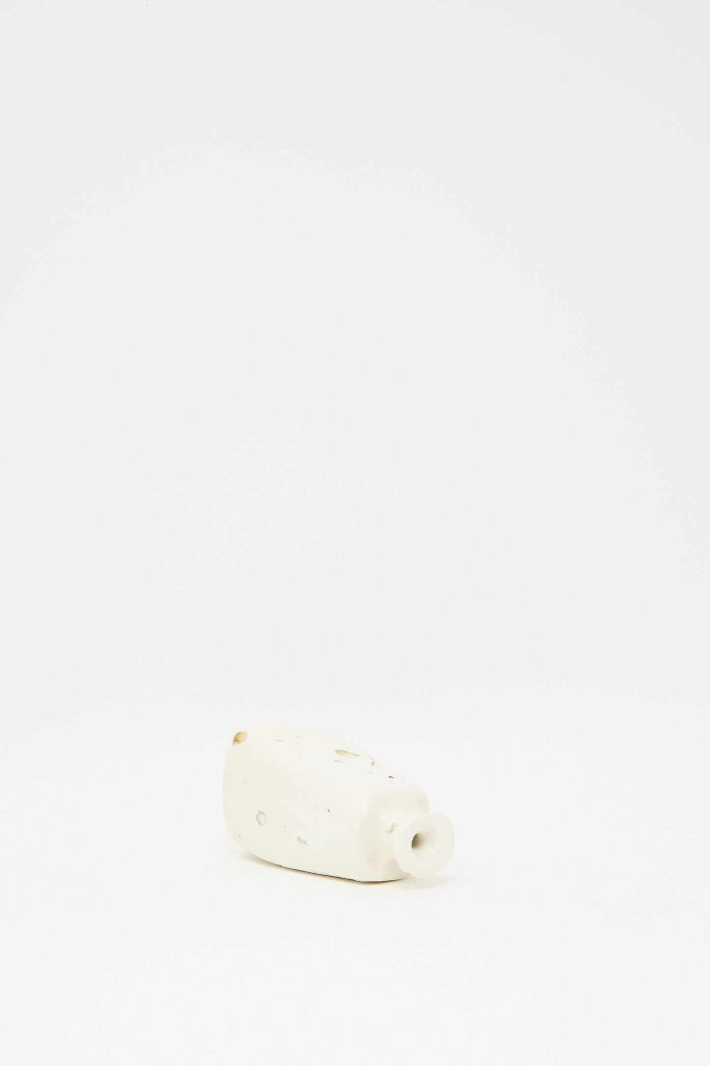The MONDAYS Carved Bud Vase I, a small white clay vase with an irregular shape and short spout, is displayed on a plain white background.