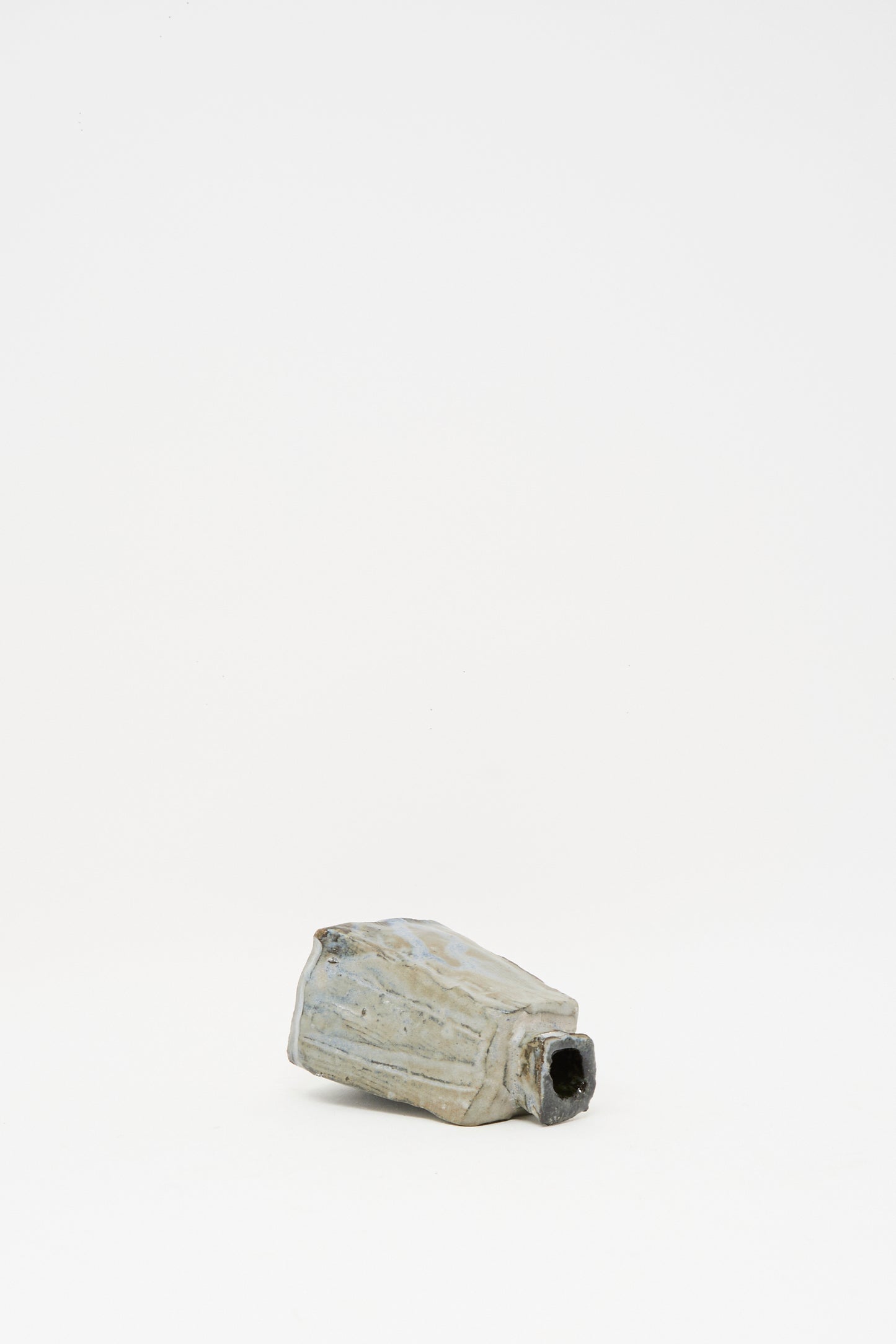 The Carved Bud Vase II by MONDAYS, a small rectangular ceramic piece with a textured finish, sits on a plain white background, exuding minimalist charm.