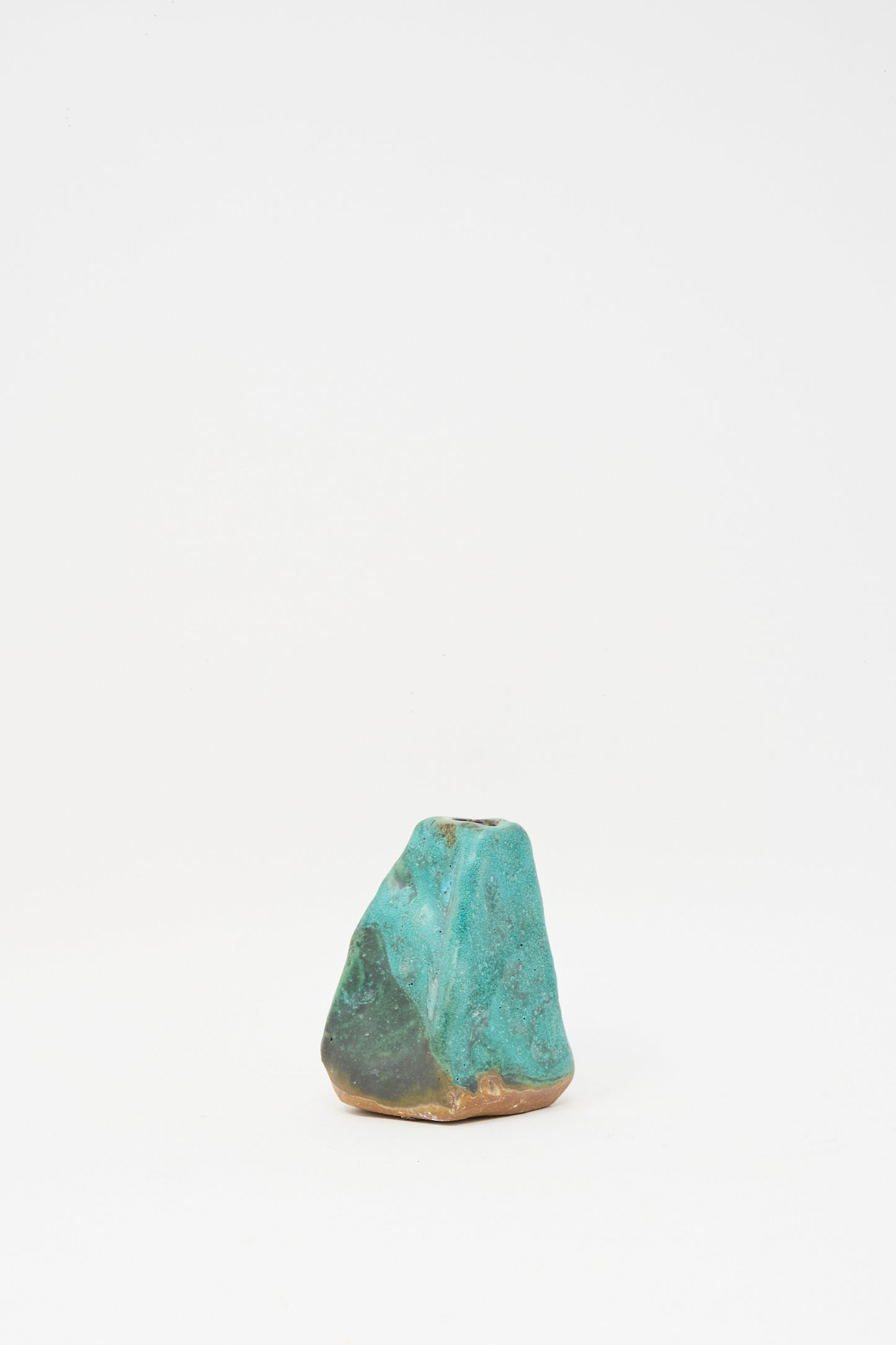 The Carved Bud Vase III by MONDAYS is a small, green clay bud vase with an irregular shape and textured surface, displayed on a plain white background.