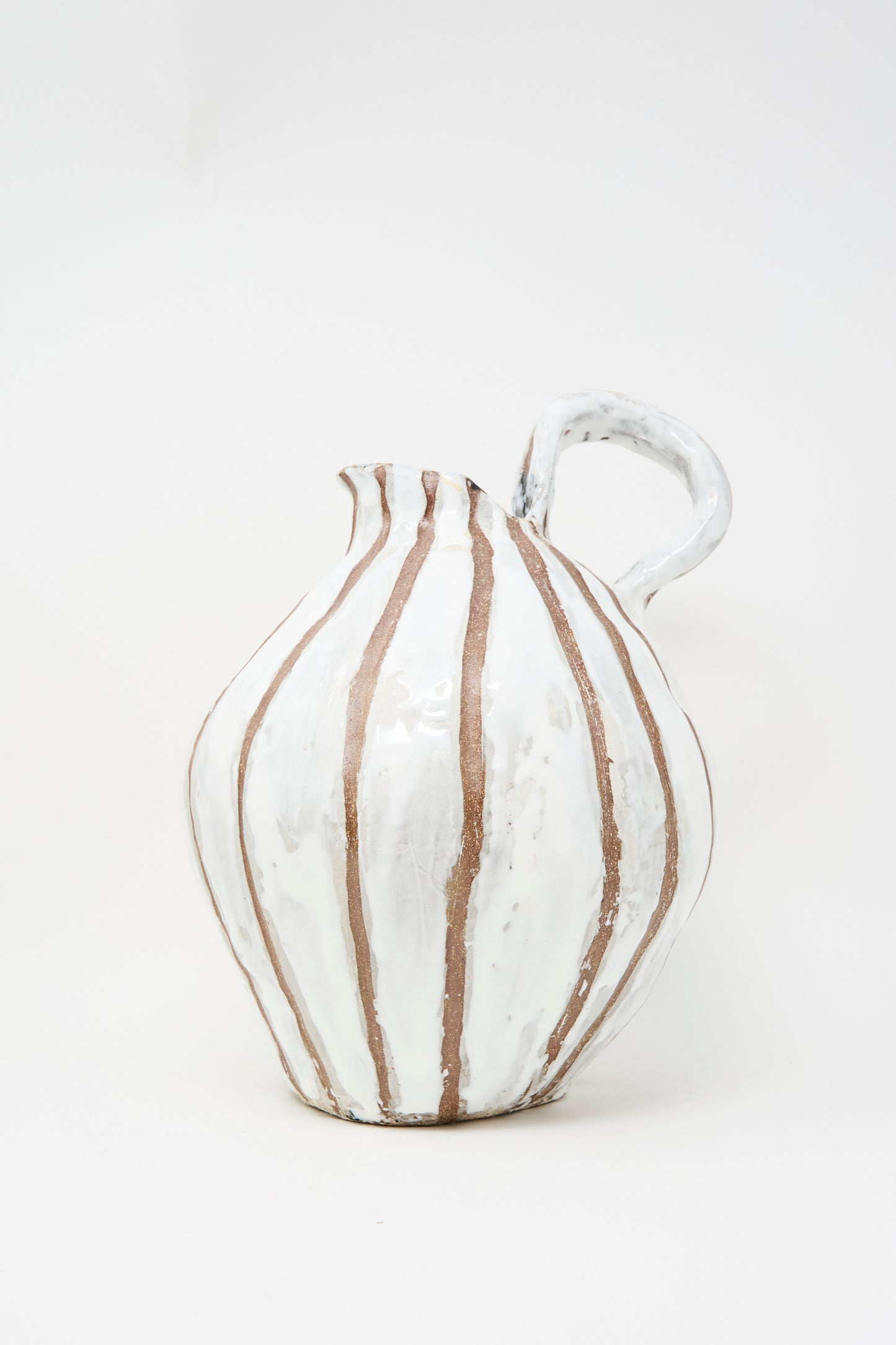 The MONDAYS Coil-built Glazed Stoneware Striped Pitcher Vase features a rounded body, curved handle, and vertical brown stripes on white. Available for in-store pickup.