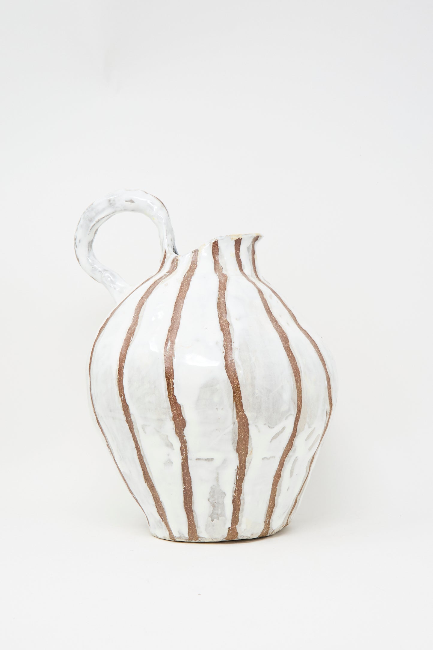 The MONDAYS Coil-built Glazed Stoneware Striped Pitcher Vase features a rounded body, narrow spout, and curved handle with a white striped glaze accented by vertical brown details.