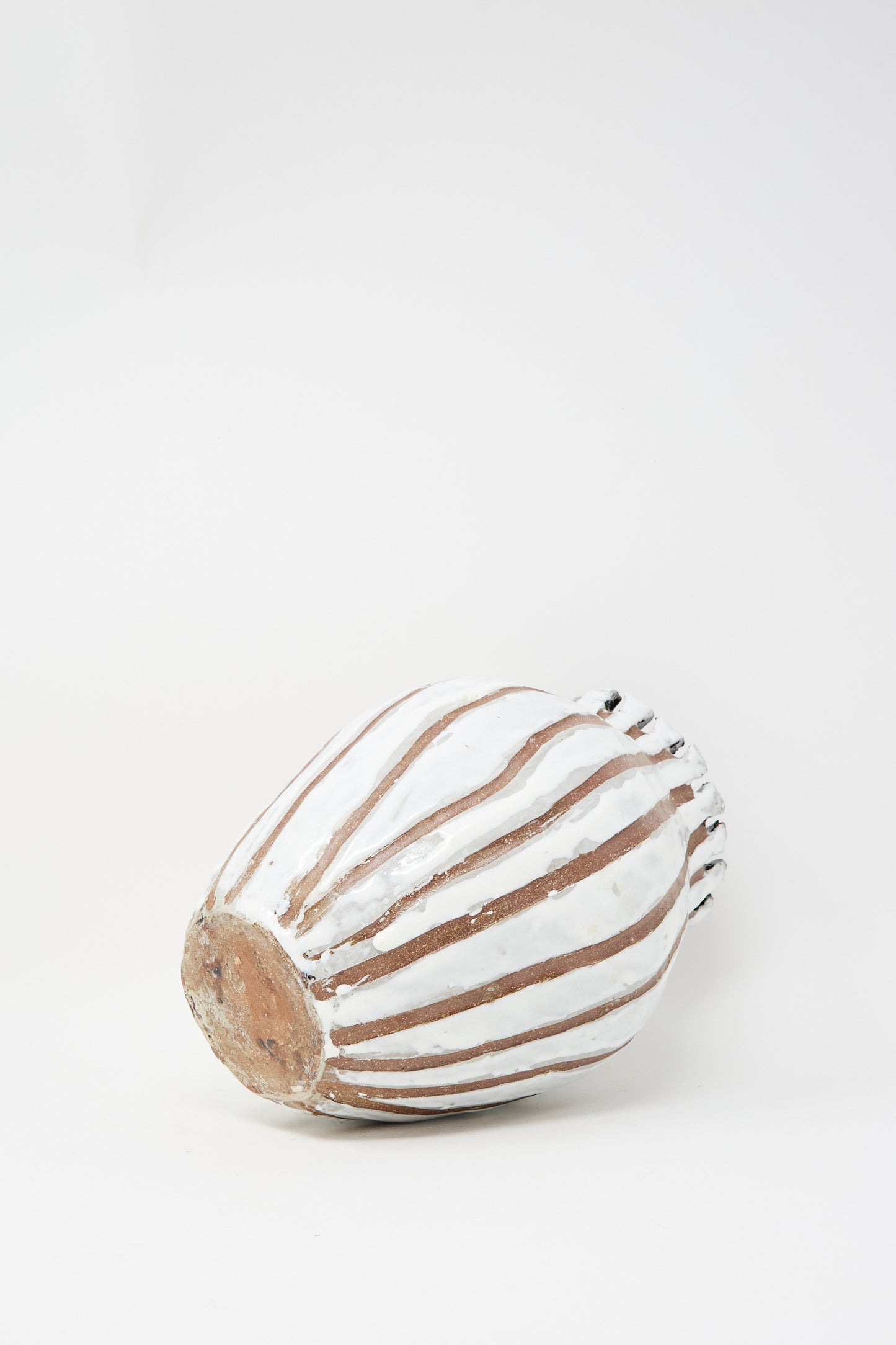 The MONDAYS Coil-built Glazed Stoneware Striped Vase, featuring white and brown stripes, is shown lying on its side against a plain white background.
