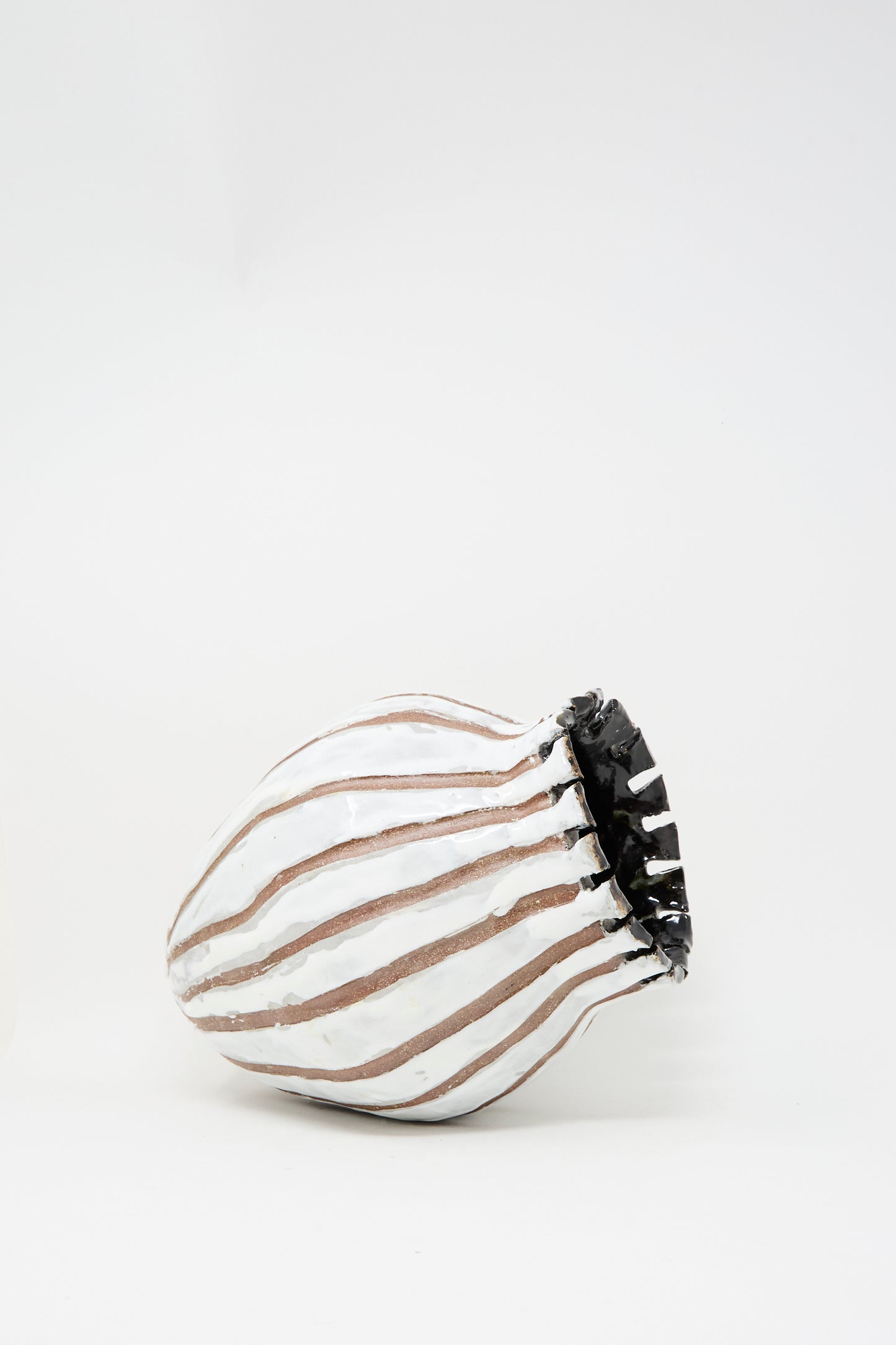The MONDAYS Coil-built Glazed Stoneware Striped Vase, featuring brown and white vertical stripes with a jagged black rim, rests on its side against a plain white background.